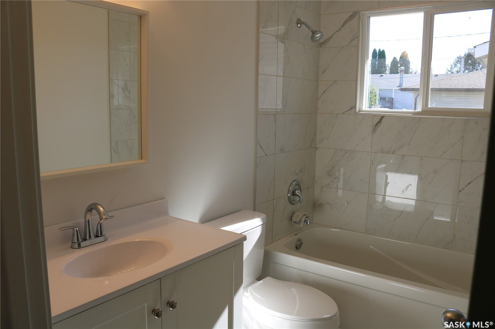 1641 Thompson Avenue, Saskatoon SK S7N 1Y2 White vanity with a single basin sink and chrome faucet, rectangular mirror, white toilet, and a bathtub with tile surround