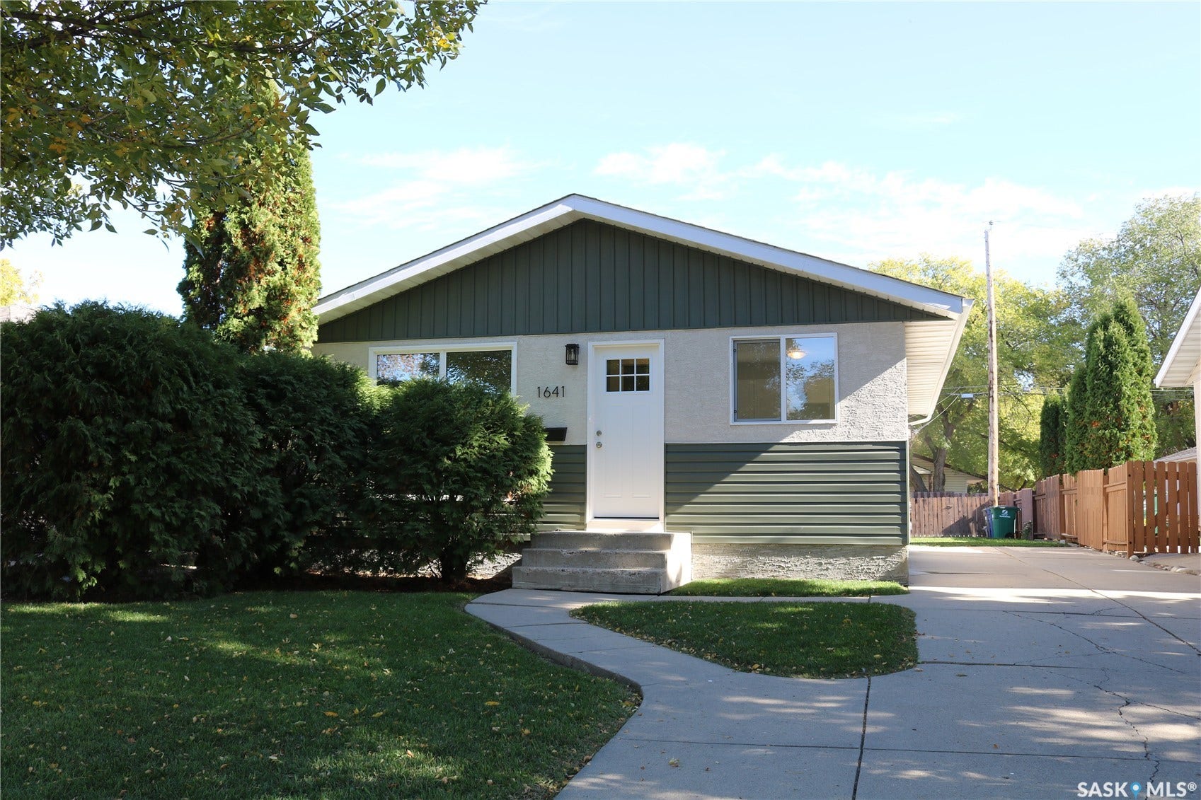 1641 Thompson Avenue, Saskatoon SK S7N 1Y2 Exterior featuring a stucco and horizontal siding facade, a white entry door with a multi-pane window, and mature front landscaping