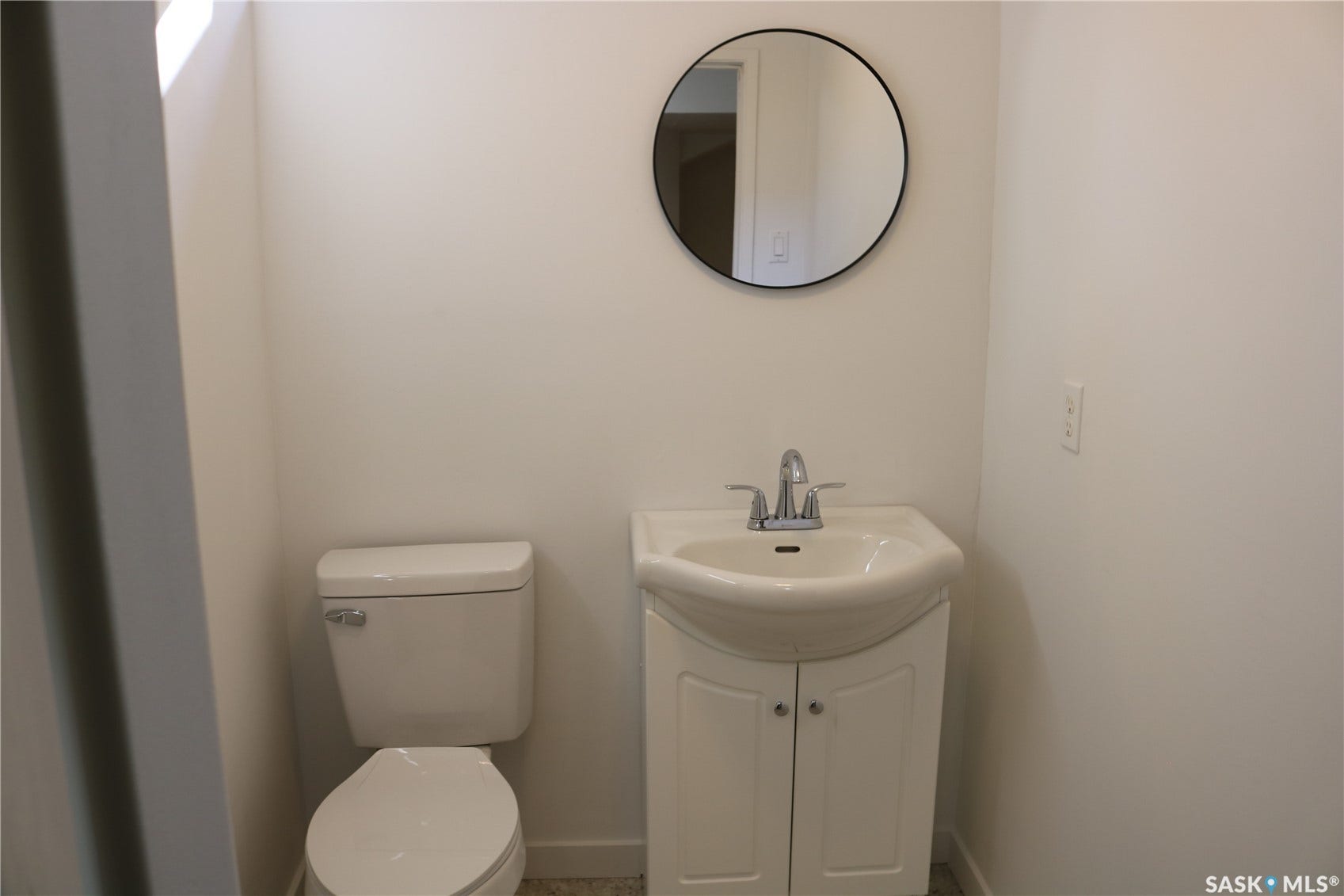 1641 Thompson Avenue, Saskatoon SK S7N 1Y2 White pedestal sink with chrome faucet, white two-door vanity, and round wall-mounted mirror