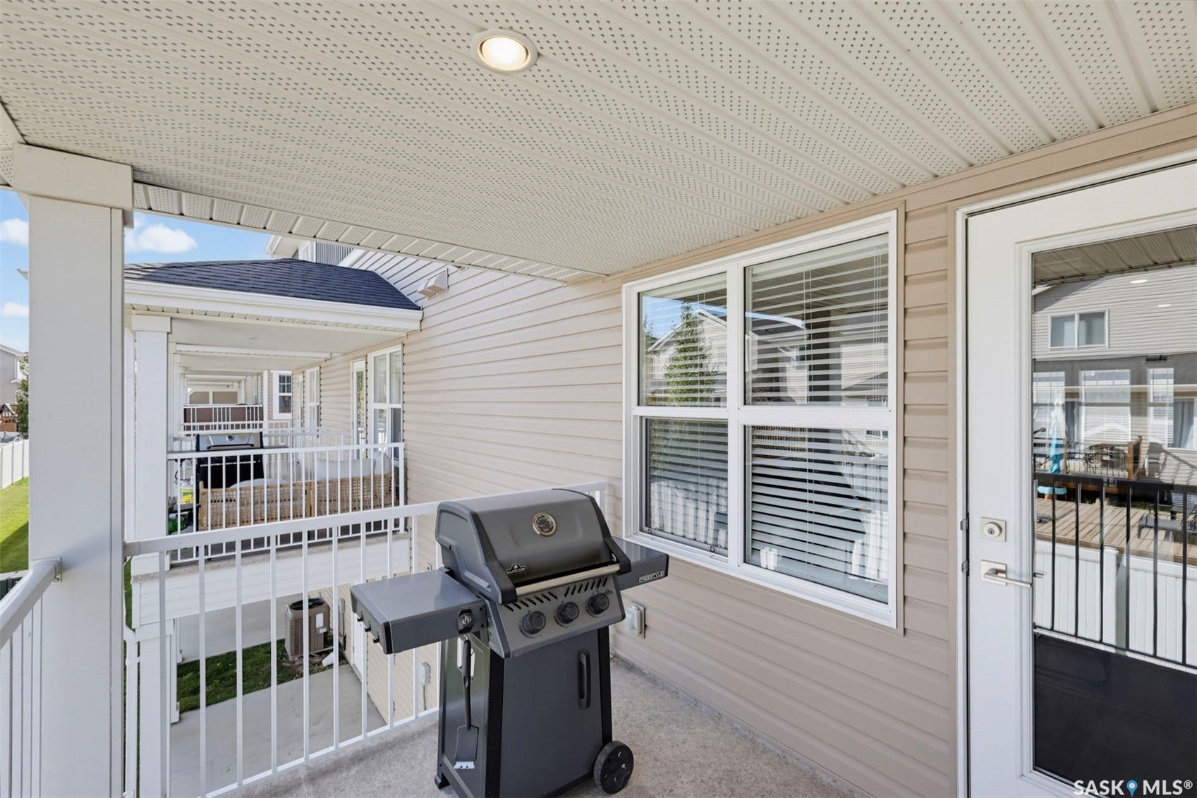 Covered balcony with a concrete surface, white railings, and an exterior light fixture