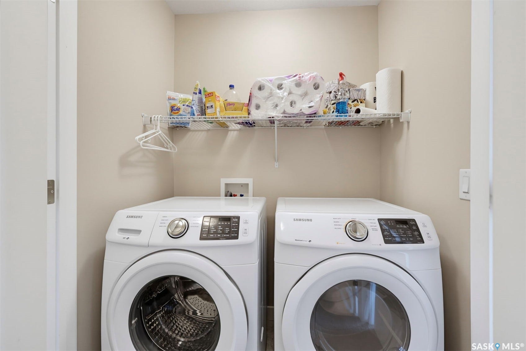 Dedicated laundry area featuring dual appliances and an overhead wire shelf
