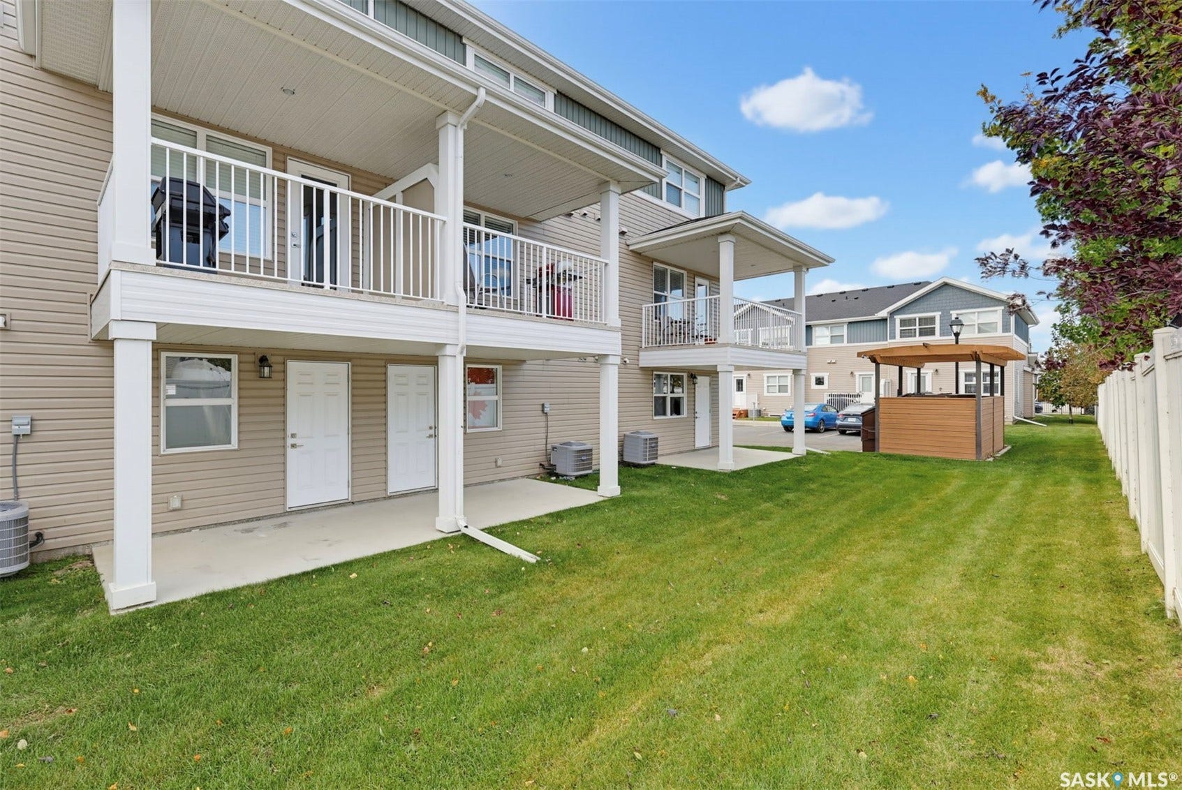 Expansive lawn area with a white privacy fence