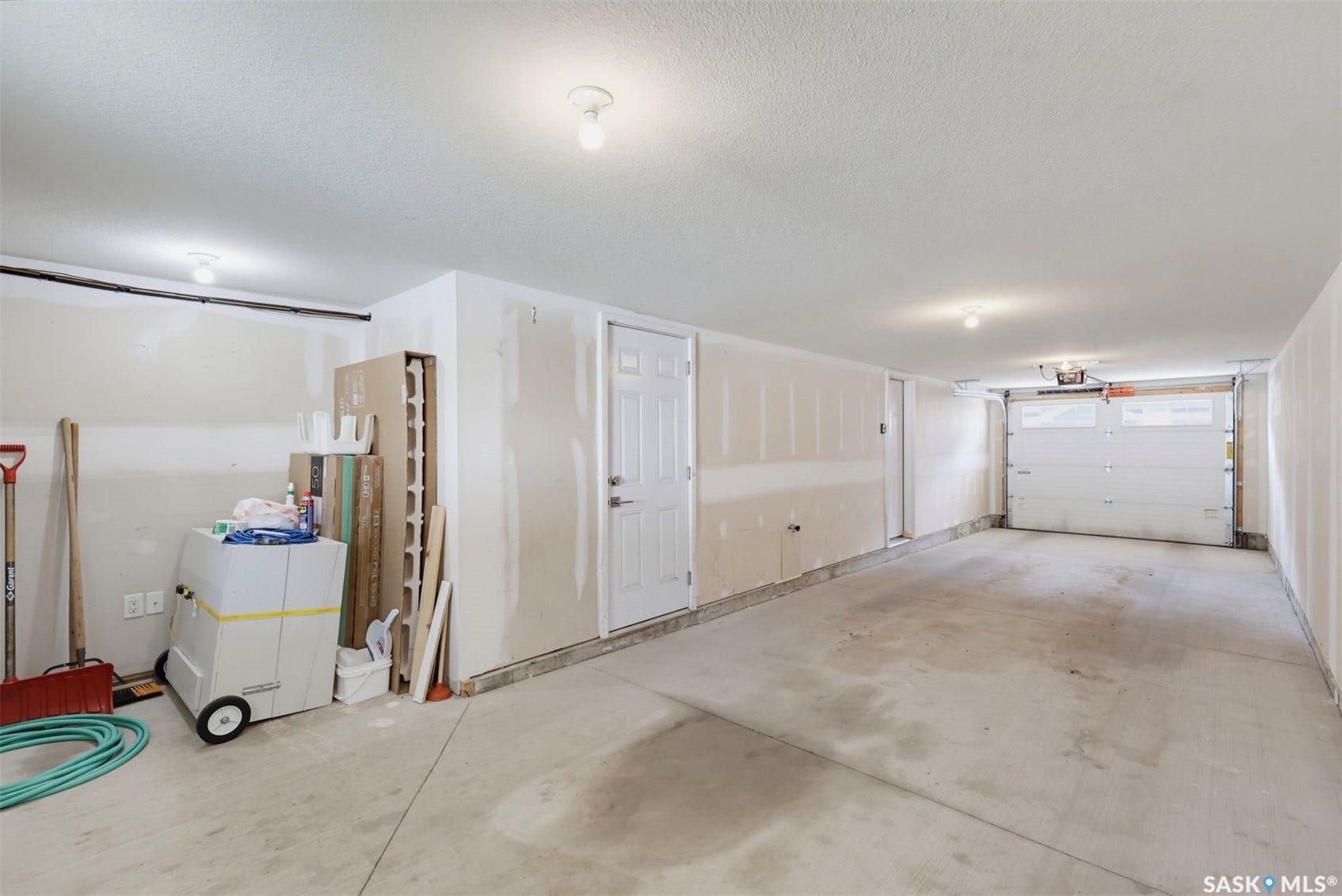 Two-car garage featuring a concrete floor, overhead lighting, and an interior access door
