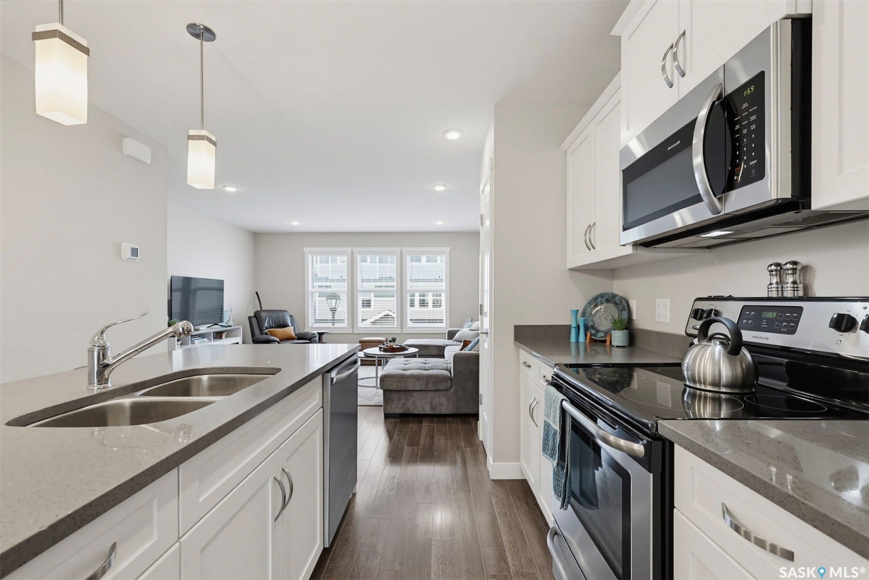Kitchen featuring white cabinetry, stainless steel appliances, a double basin sink, and pendant lighting