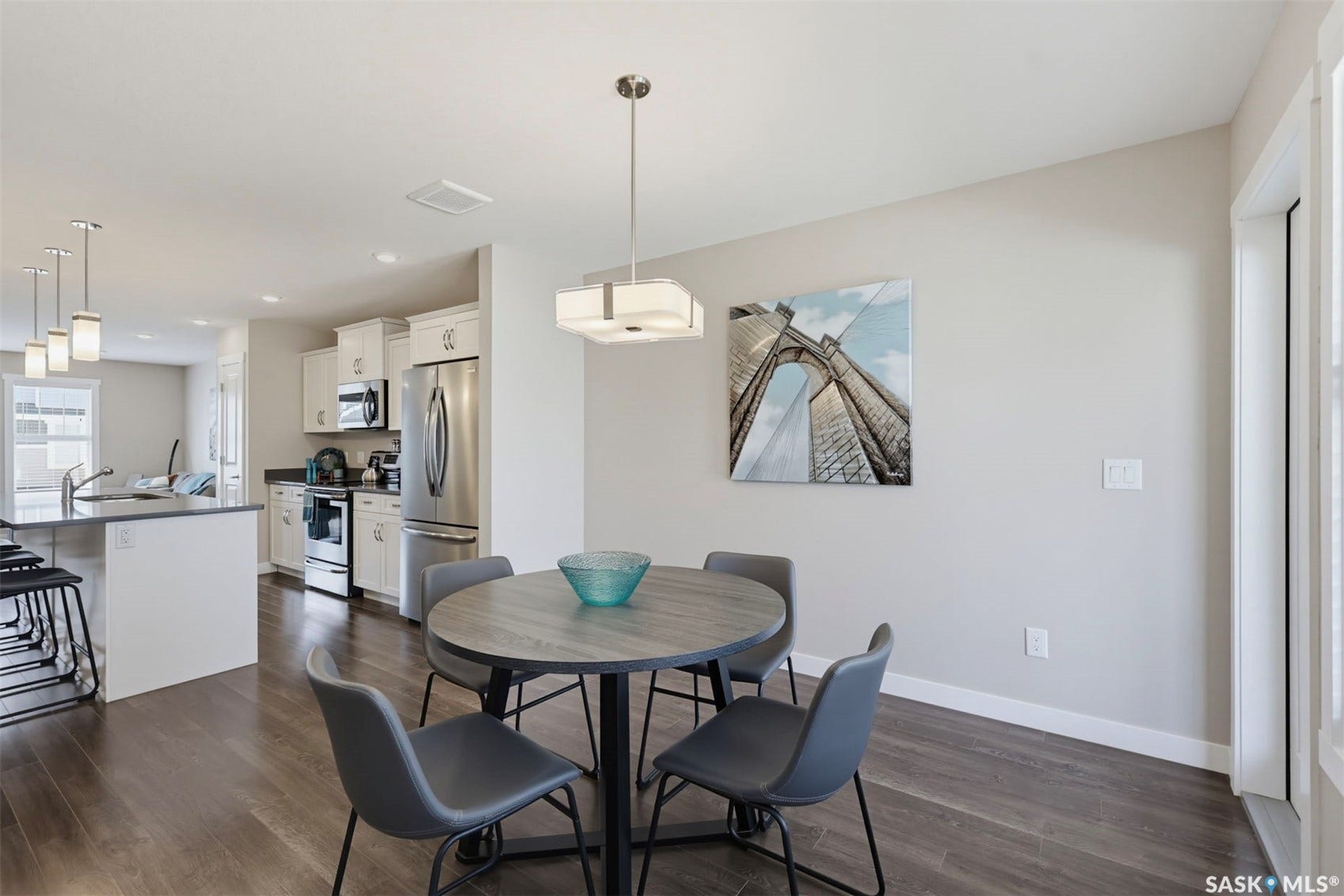 Open concept design with wood-finish flooring, white cabinetry, dark countertops, and stainless steel appliances