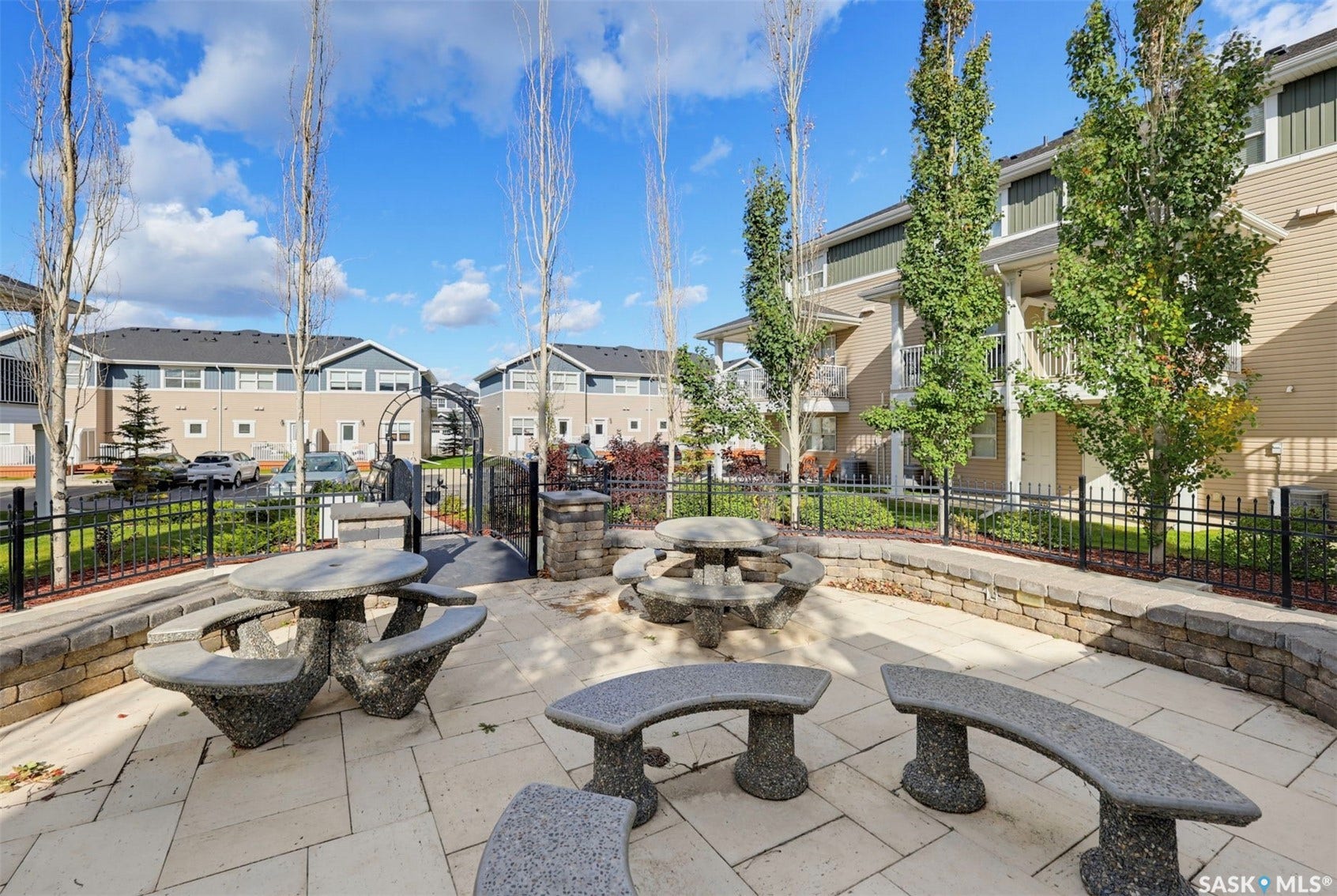 Paved patio area with stone benches and picnic tables, surrounded by a low stone retaining wall