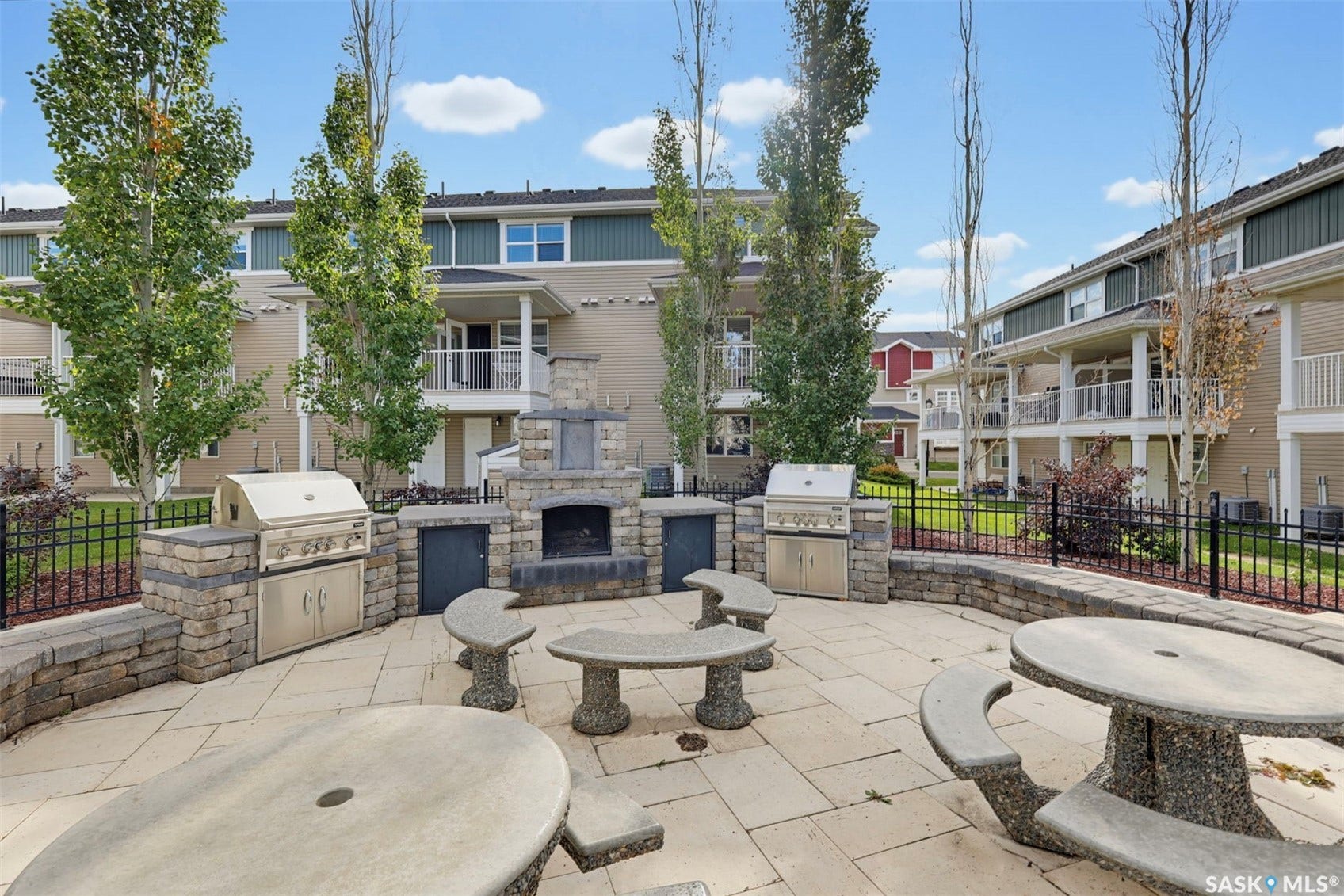 Stone paver patio featuring a built-in outdoor fireplace and two stainless steel grills