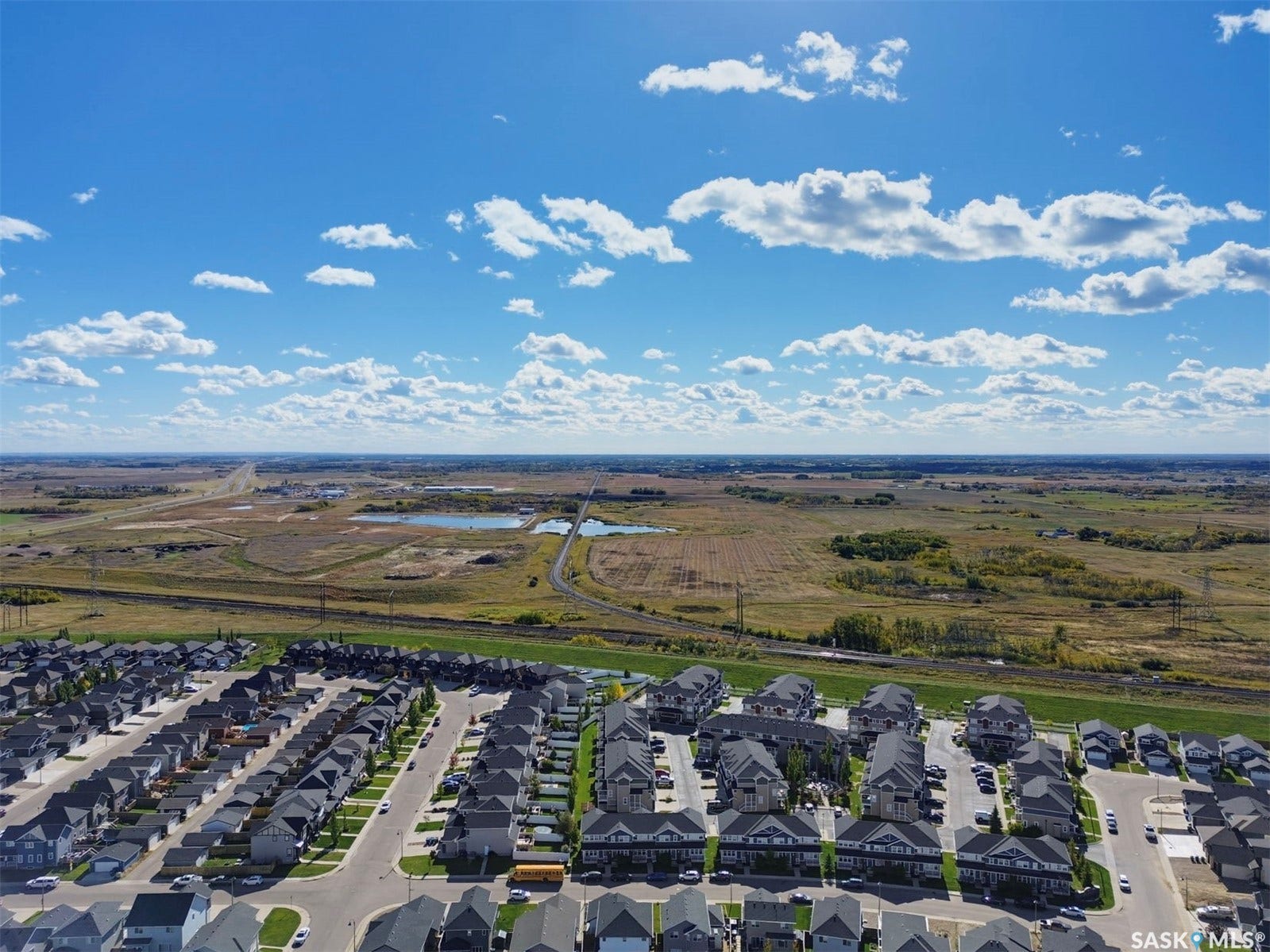 Expansive neighborhood with rows of residential homes, visible roads, and distant natural landscapes featuring bodies of water