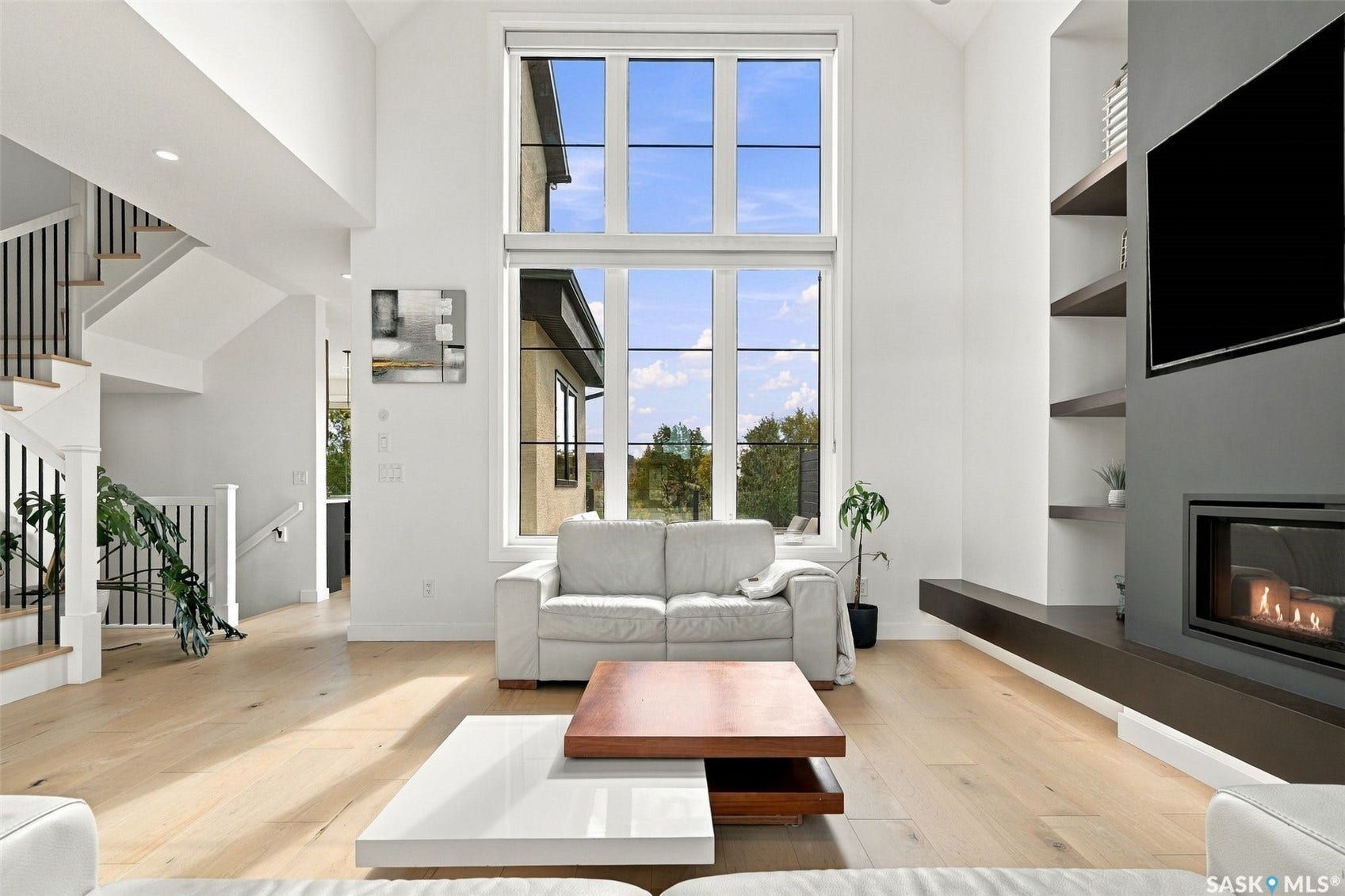 6221 Koep Avenue, Regina SK S4X 0J2 Two-story living area featuring a large multi-pane window, light wood-finish flooring, a built-in fireplace, and floating shelving
