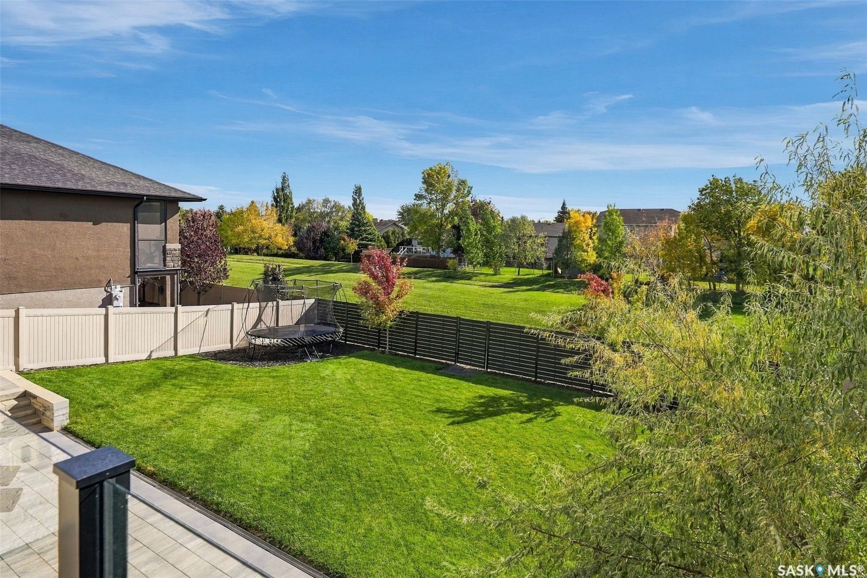 6221 Koep Avenue, Regina SK S4X 0J2 Expansive backyard featuring a manicured lawn, paved patio, and a combination of privacy and slat fencing