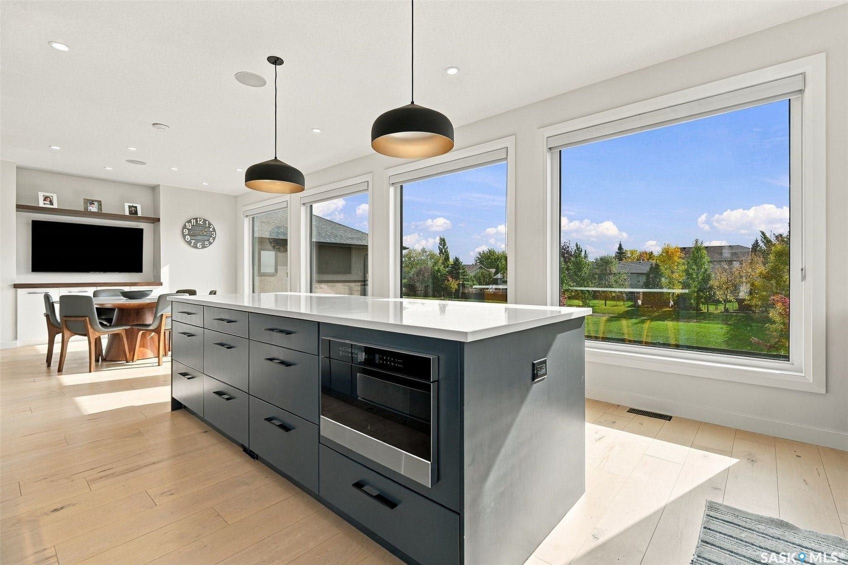 6221 Koep Avenue, Regina SK S4X 0J2 Central kitchen island with an integrated microwave drawer, light wood-finish flooring, and large windows