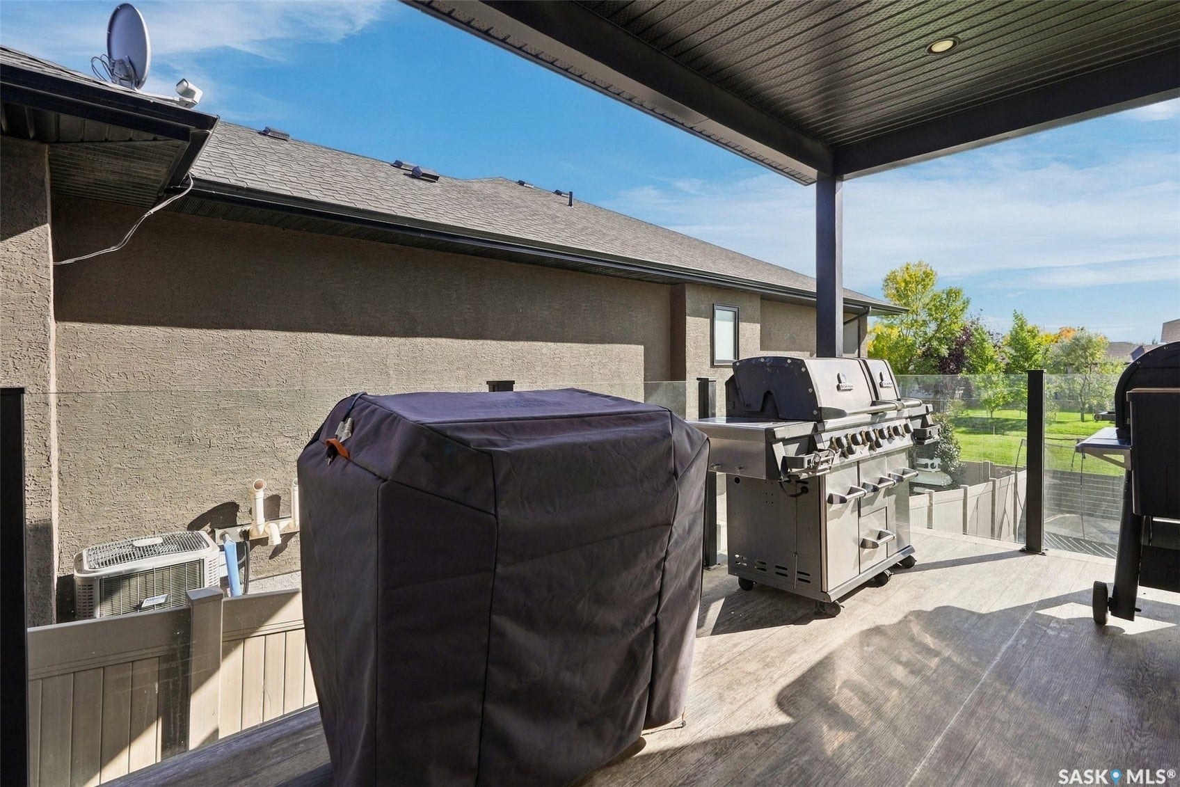 6221 Koep Avenue, Regina SK S4X 0J2 Covered outdoor patio with a plank-style floor, glass panel railing, and recessed ceiling lighting