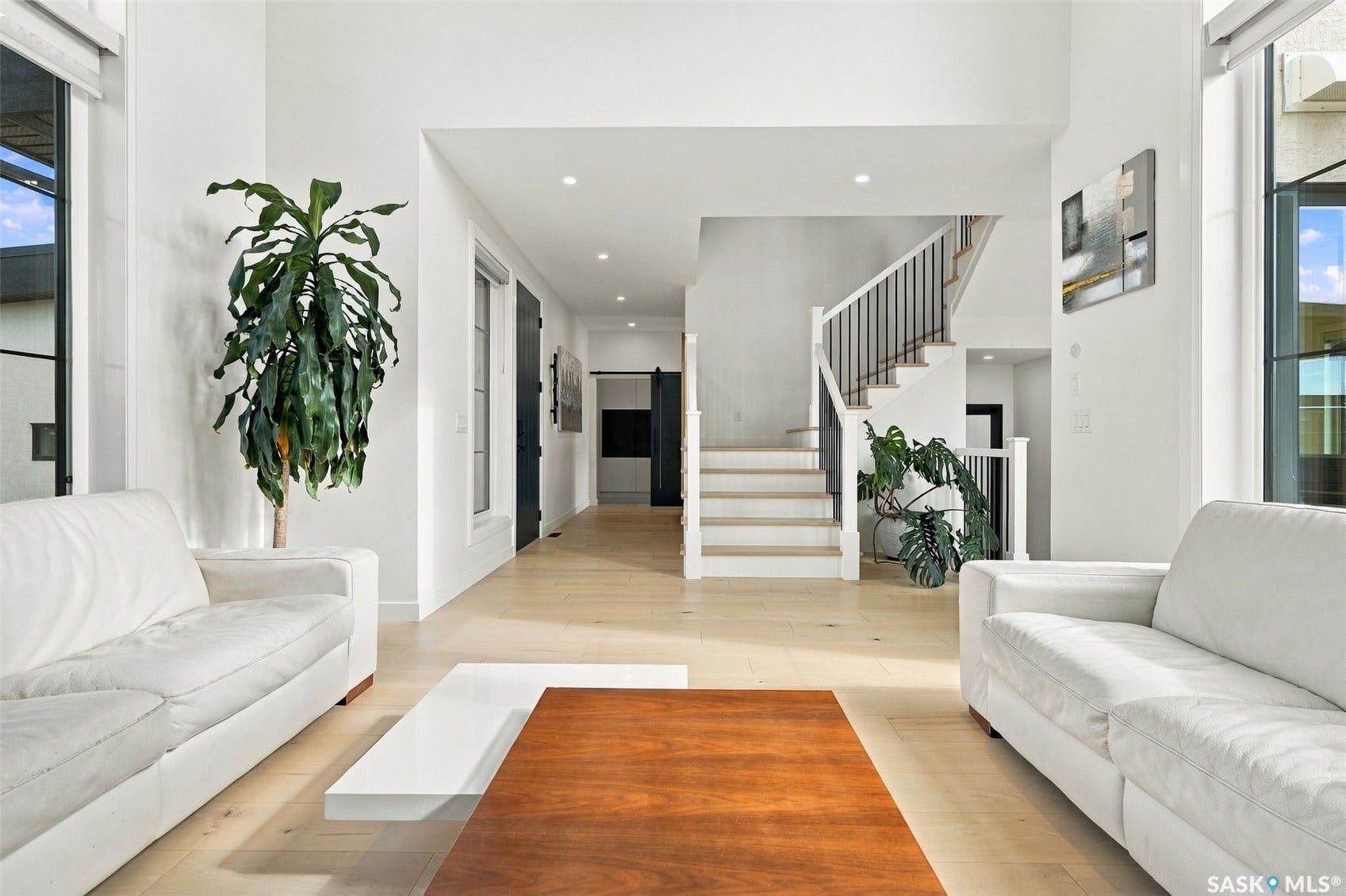 6221 Koep Avenue, Regina SK S4X 0J2 Open concept living space featuring light wood-finish flooring, recessed lighting, and a prominent staircase with dark metal balusters