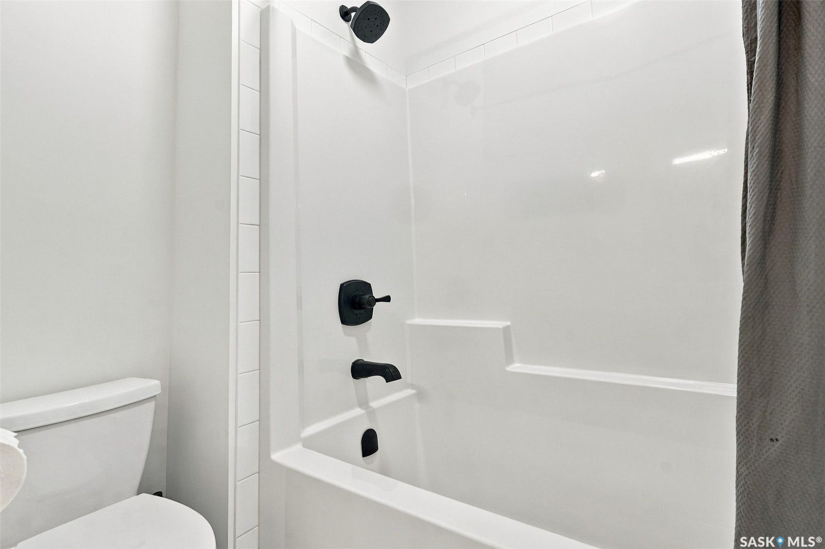 6221 Koep Avenue, Regina SK S4X 0J2 Bathtub with integrated shelving, matte black fixtures, and a shower/tub combination
