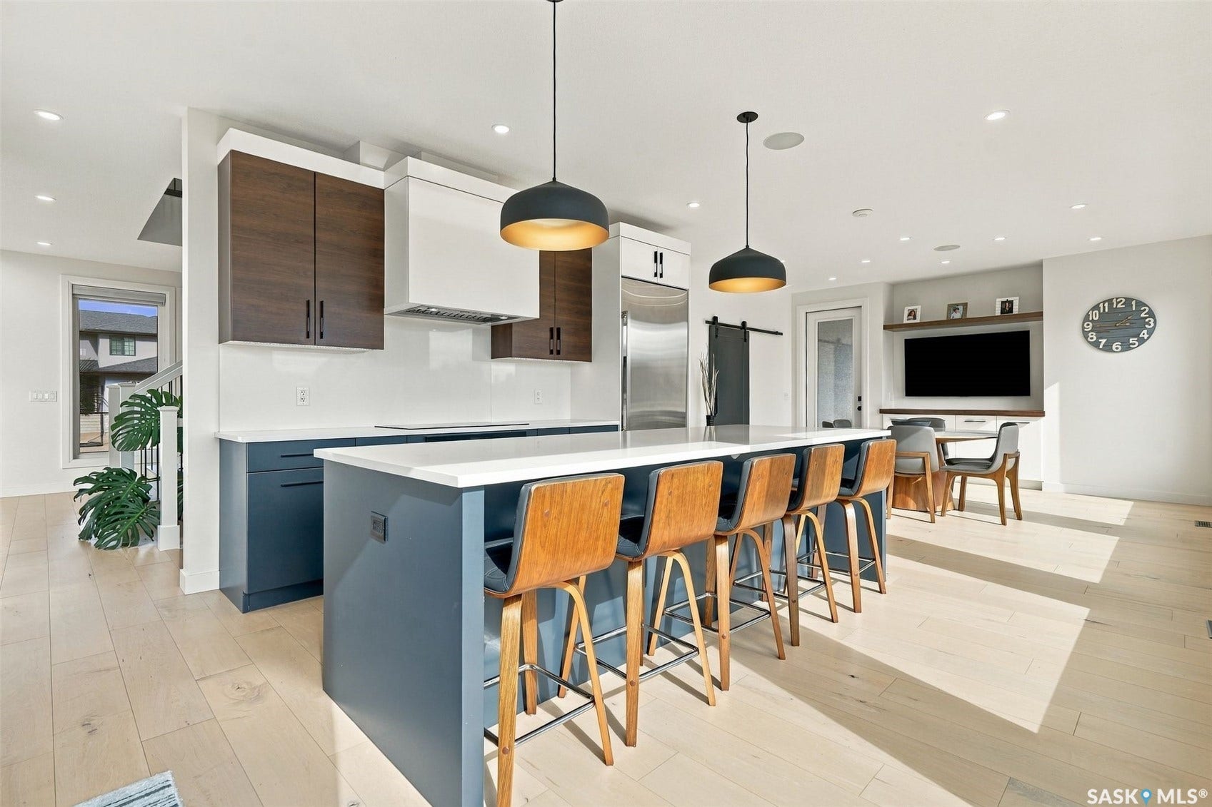 6221 Koep Avenue, Regina SK S4X 0J2 Open-concept kitchen with a large island featuring a white countertop, two-tone cabinetry with dark wood and blue finishes, and light wood-finish flooring