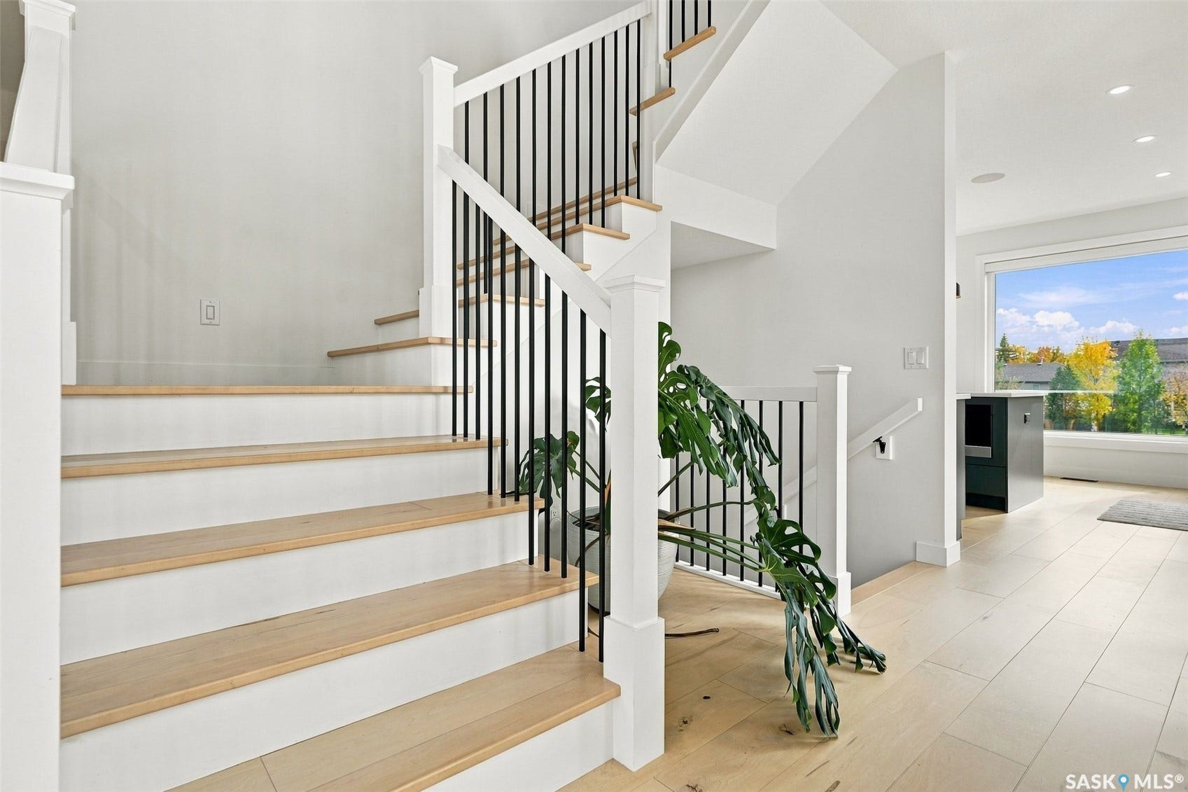 6221 Koep Avenue, Regina SK S4X 0J2 Hardwood flooring and staircase with white risers and black metal balusters
