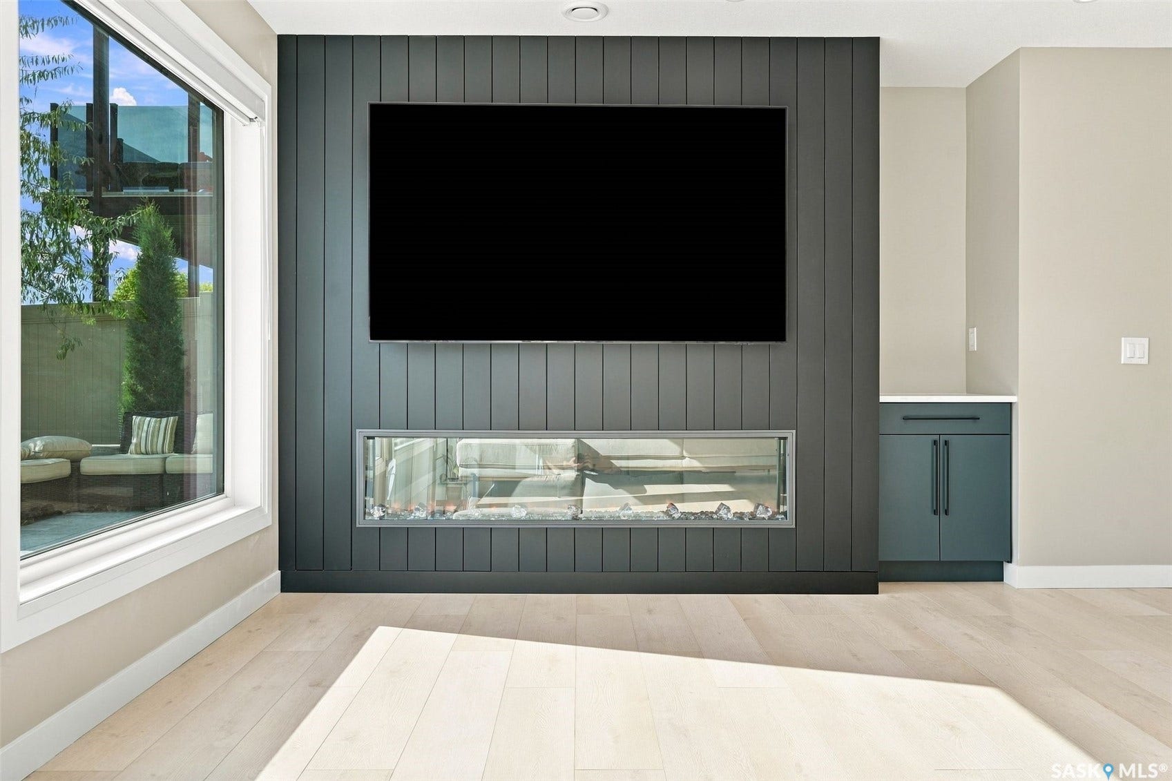 6221 Koep Avenue, Regina SK S4X 0J2 Wide plank wood-finish flooring, full-height window, contemporary linear fireplace, and built-in cabinetry with a countertop