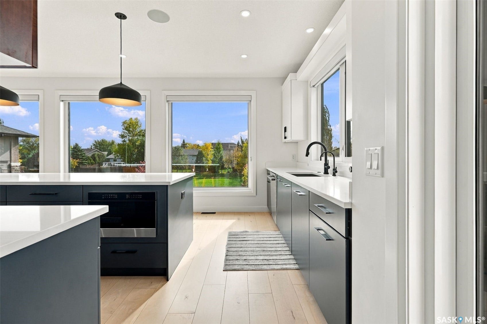 6221 Koep Avenue, Regina SK S4X 0J2 Modern kitchen featuring light wood-finish flooring, white countertops, and dark cabinetry