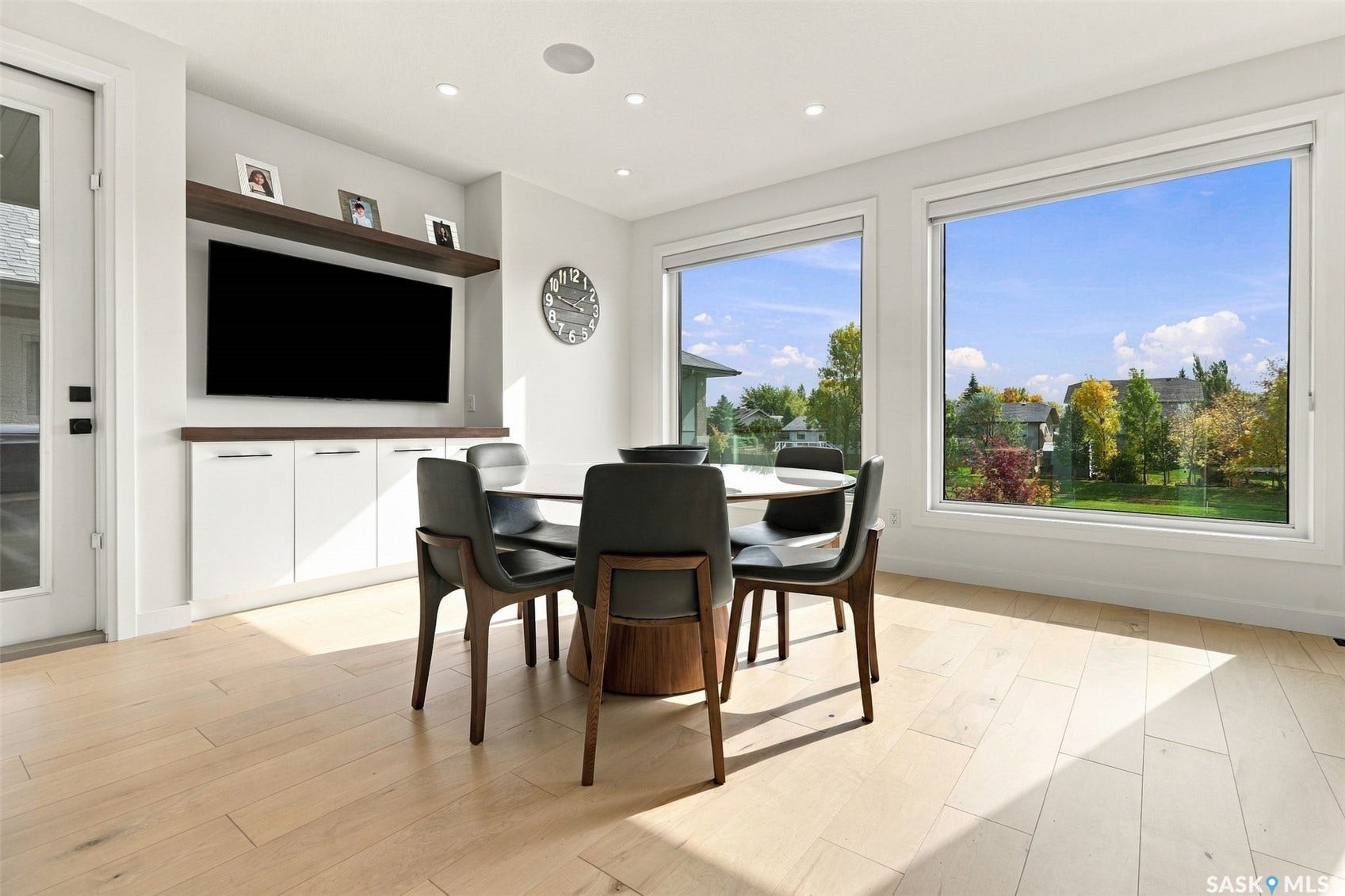 6221 Koep Avenue, Regina SK S4X 0J2 Light wood-finish flooring, built-in entertainment center with white cabinetry, floating wood-finish shelf, recessed lighting, and large windows