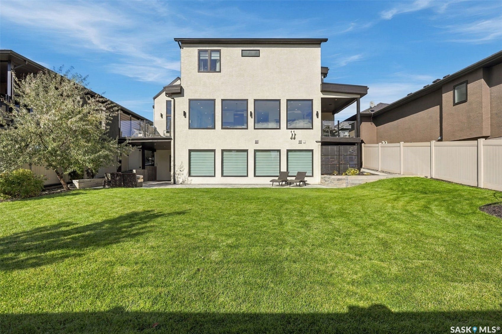 6221 Koep Avenue, Regina SK S4X 0J2 Expansive rear yard with a manicured lawn, complete with a privacy fence and a second-story covered patio