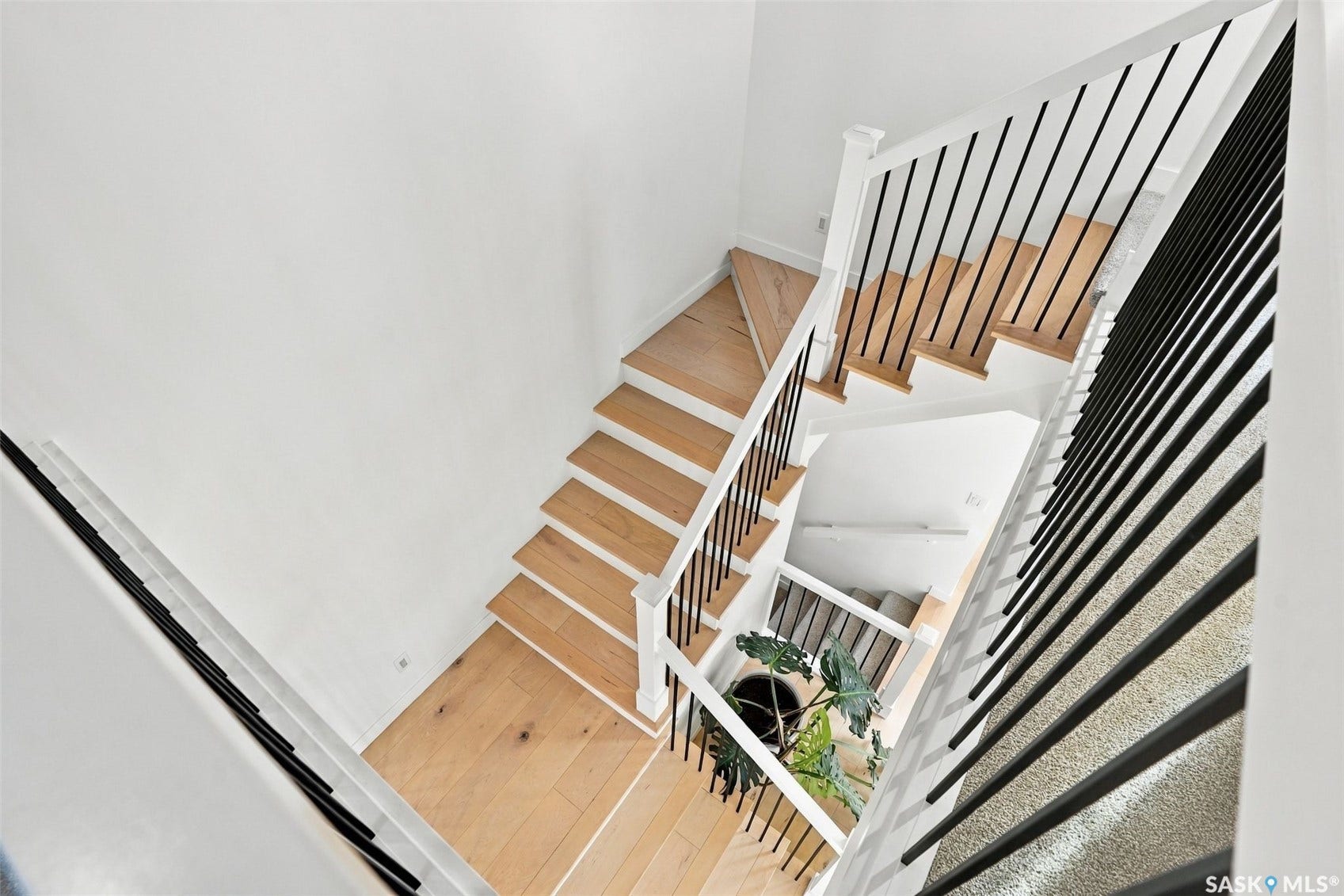 6221 Koep Avenue, Regina SK S4X 0J2 Multi-level staircase featuring light wood-finish treads, white risers, and contemporary black metal spindles