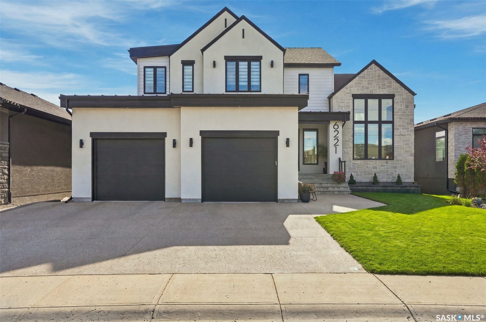 6221 Koep Avenue, Regina SK S4X 0J2 Contemporary exterior with stucco and stone accents, two-car garage, large picture window, well-maintained lawn, and a concrete driveway