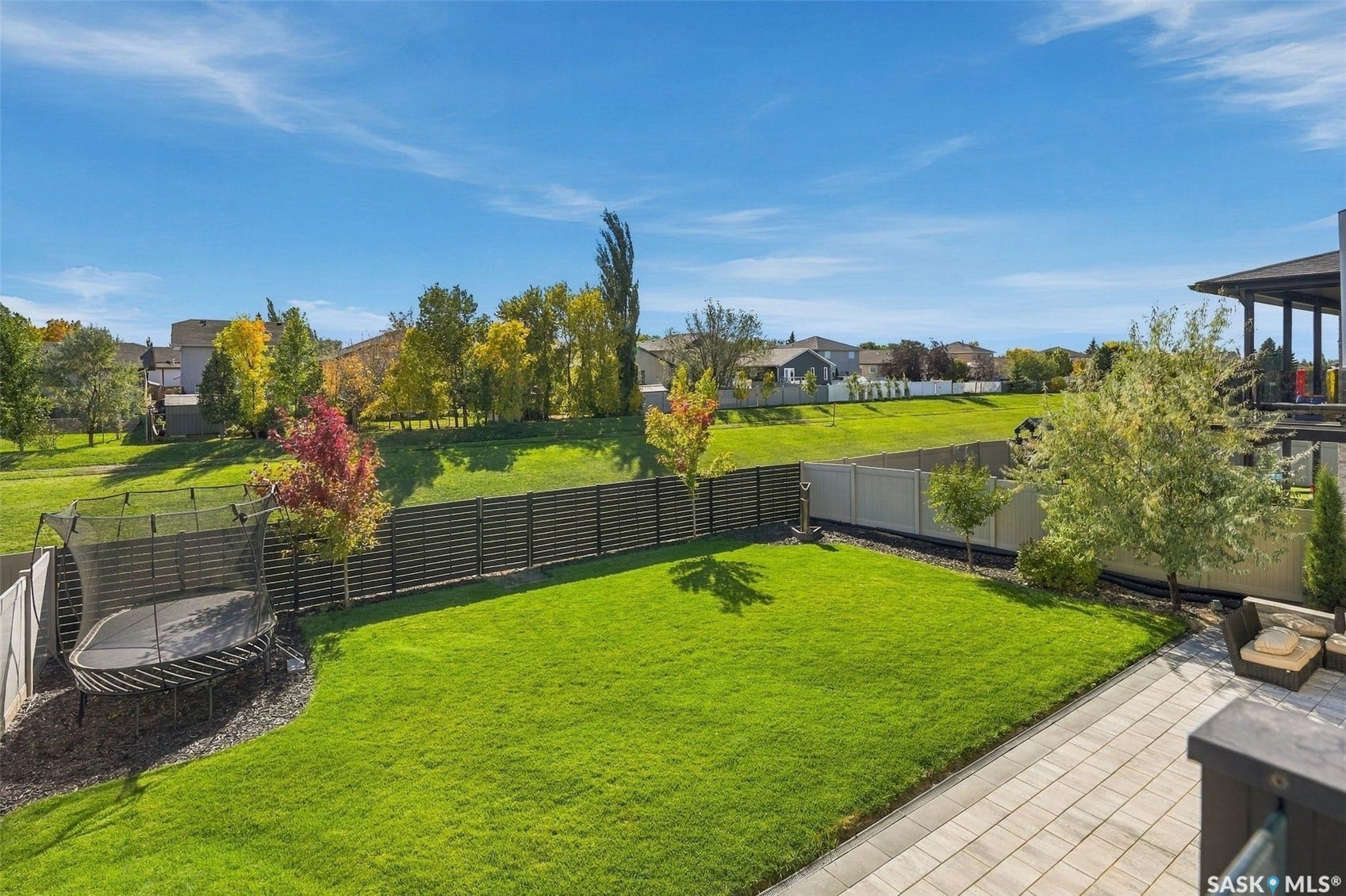 6221 Koep Avenue, Regina SK S4X 0J2 Expansive backyard featuring a manicured lawn, mature trees, and a paver patio
