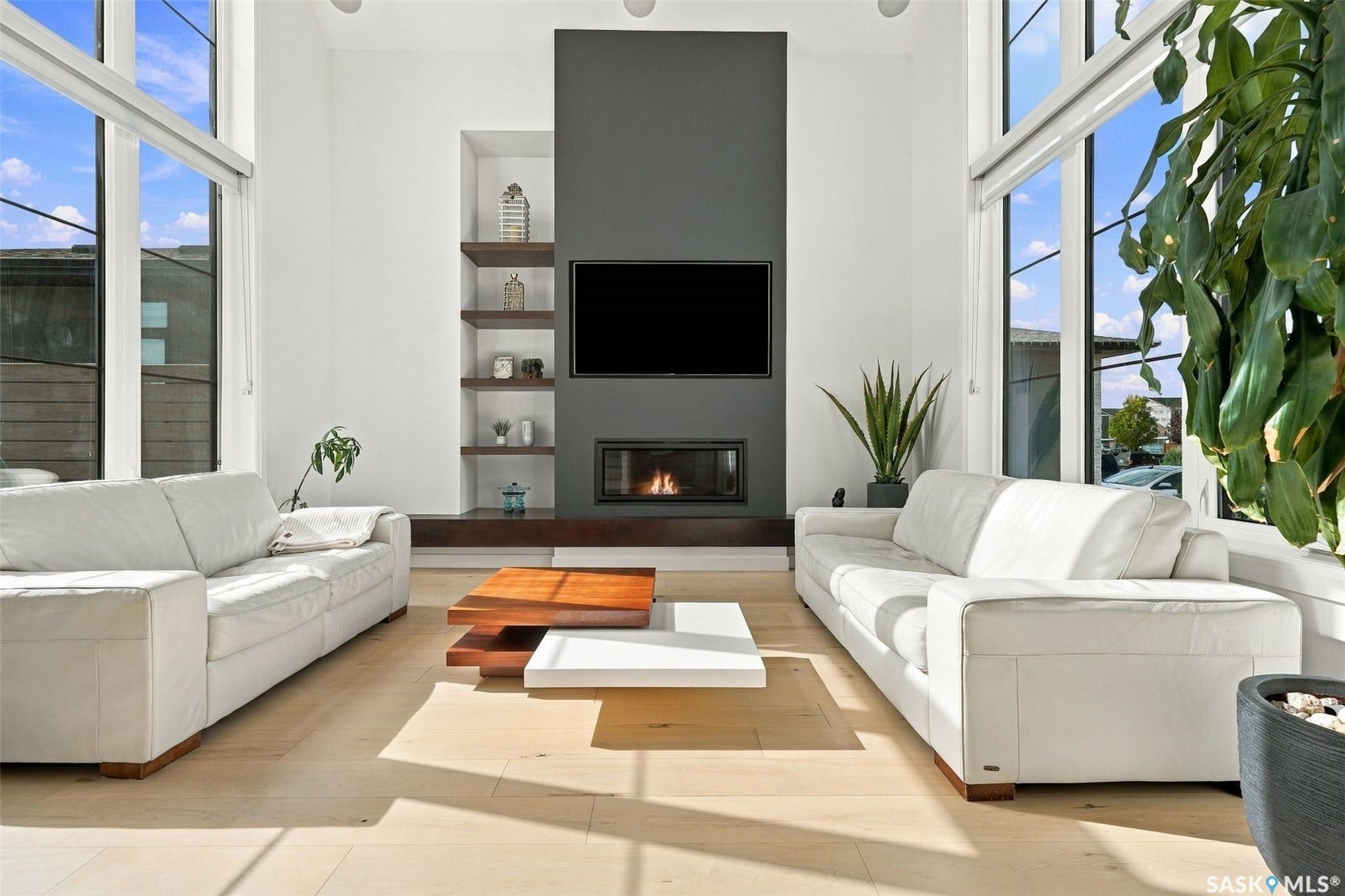6221 Koep Avenue, Regina SK S4X 0J2 Integrated fireplace with a dark accent wall, built-in shelving, soaring windows with roller shades, recessed lighting, and light wood-finish flooring