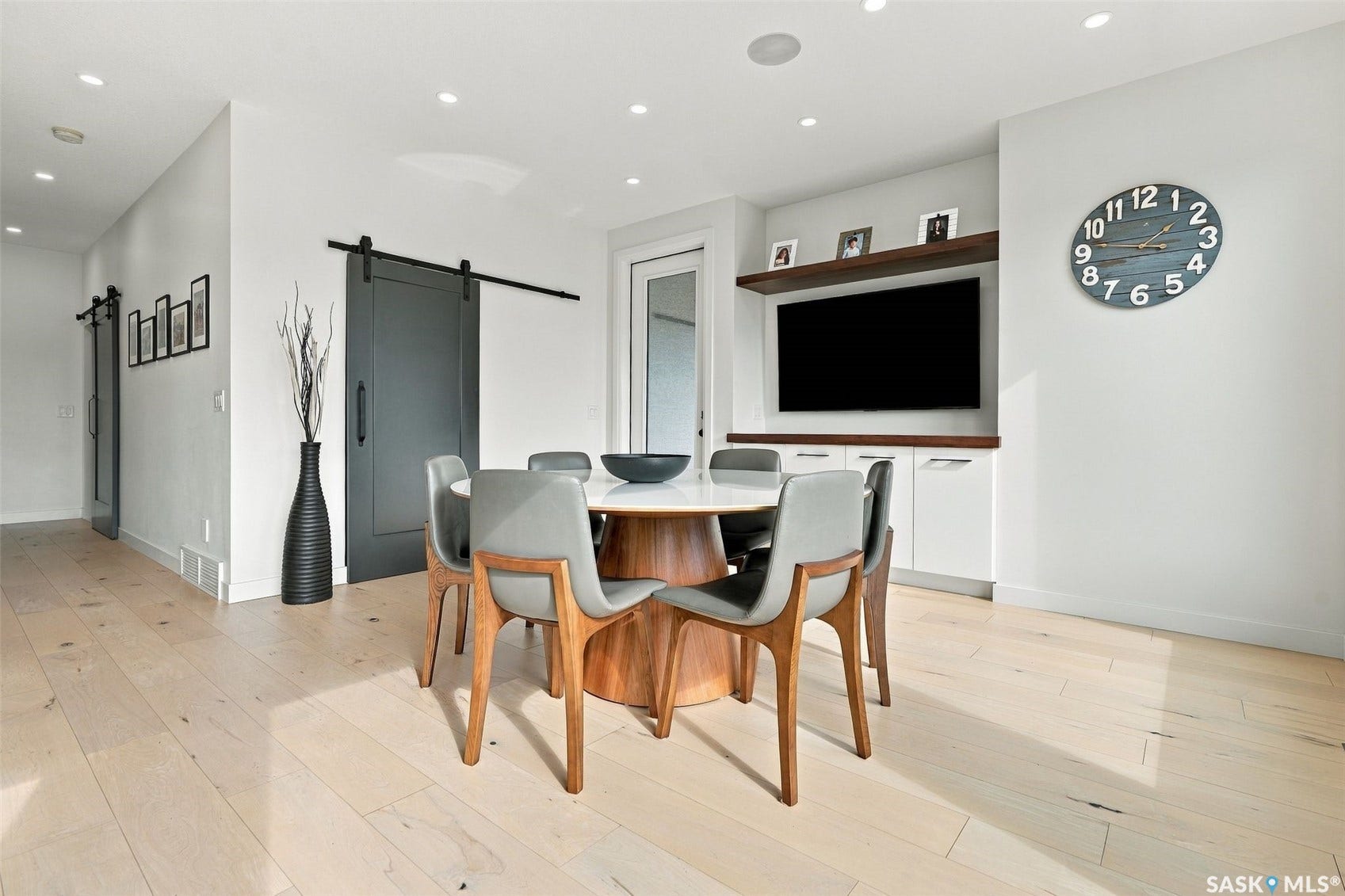 6221 Koep Avenue, Regina SK S4X 0J2 Light wood-finish flooring, recessed ceiling lighting, built-in entertainment center with white cabinetry, and a dark barn door