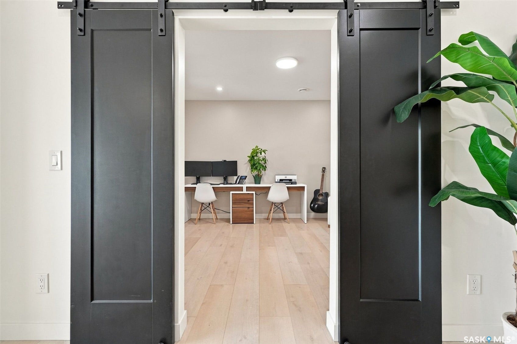 6221 Koep Avenue, Regina SK S4X 0J2 Two dark-paneled sliding barn doors with black hardware, light wood-finish flooring, recessed lighting, and white walls
