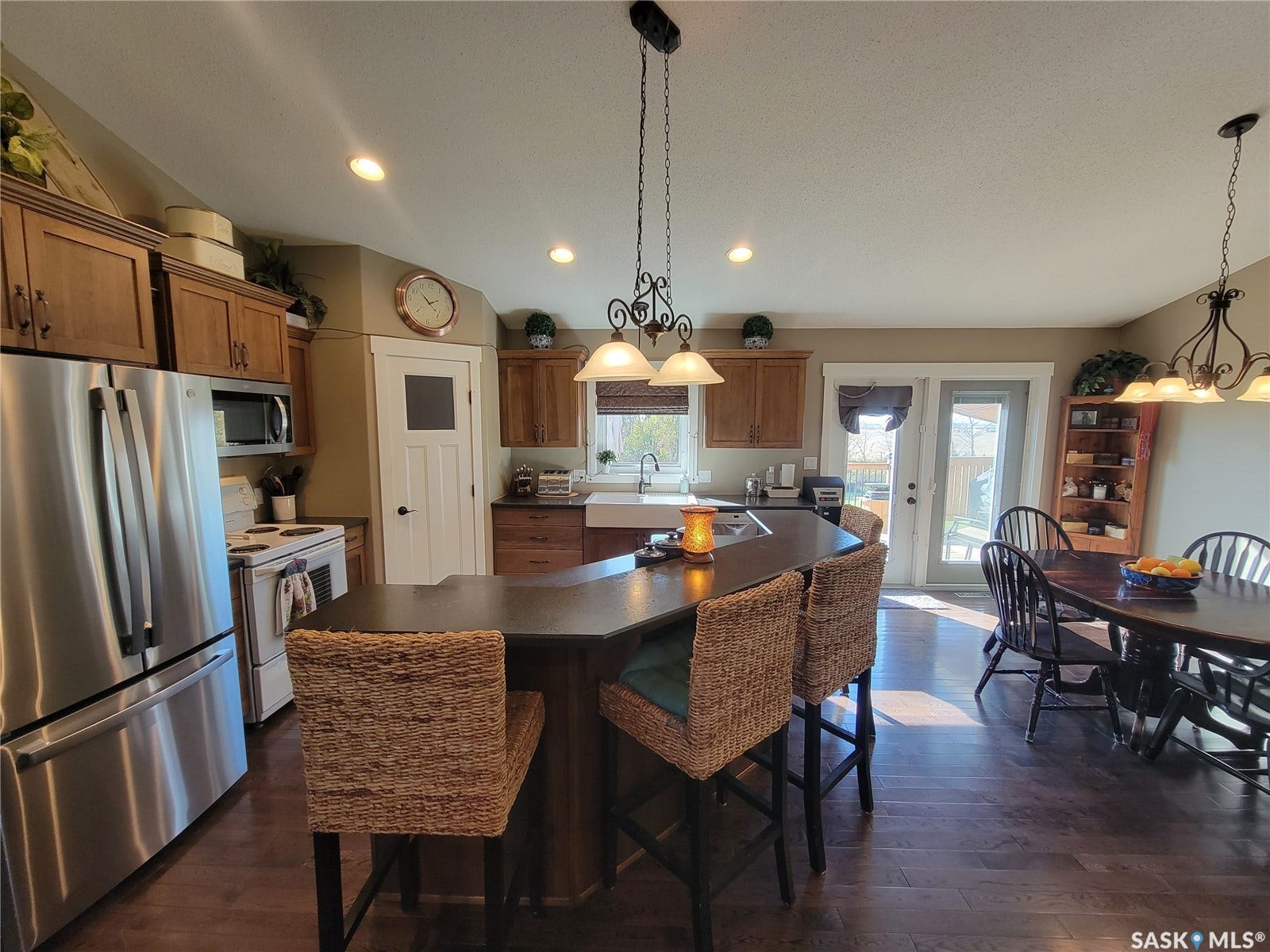 Kitchen featuring stainless steel appliances, wood-finish flooring, recessed lighting, wood cabinetry, and a central island with seating