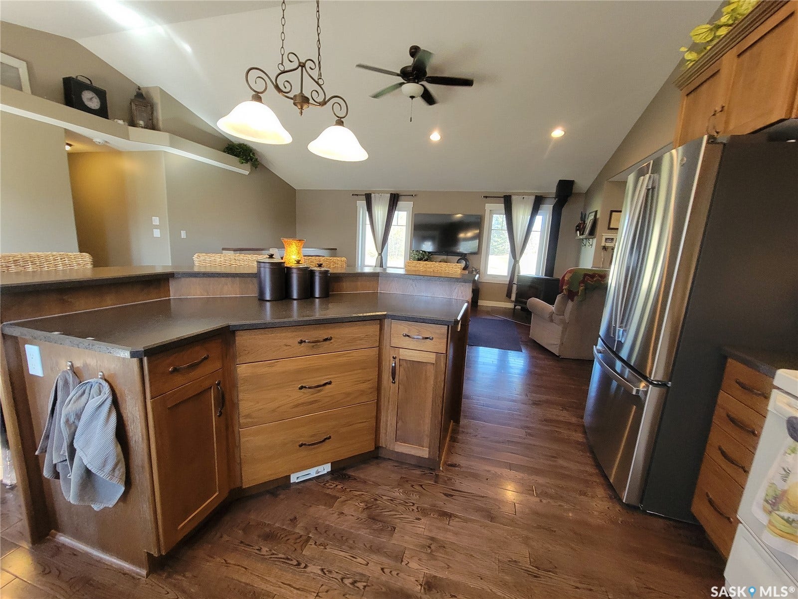 Kitchen with wood-finish cabinetry, dark countertops, and stainless steel refrigerator