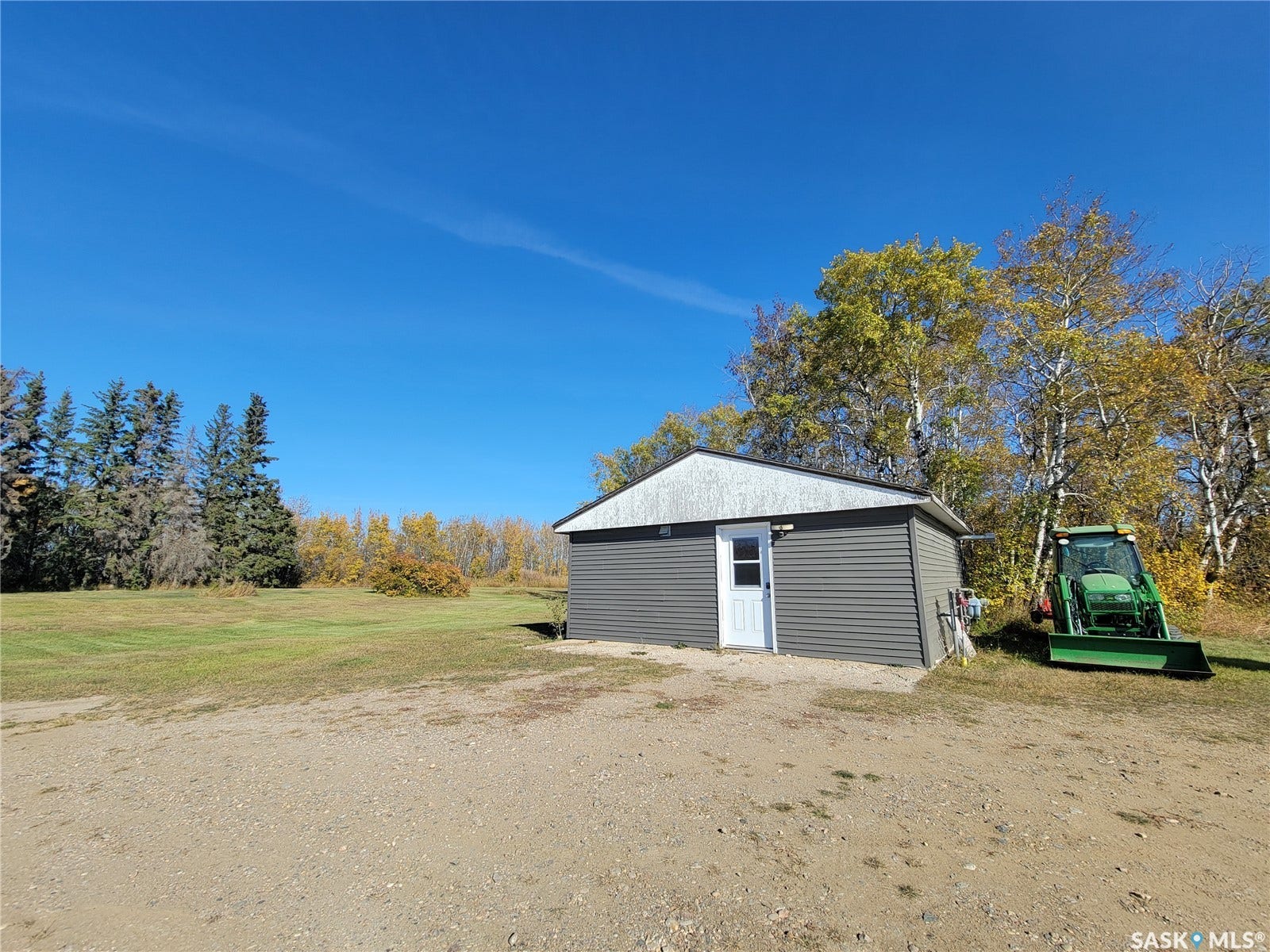 Detached garage with horizontal siding, a white entry door, and a metal roof