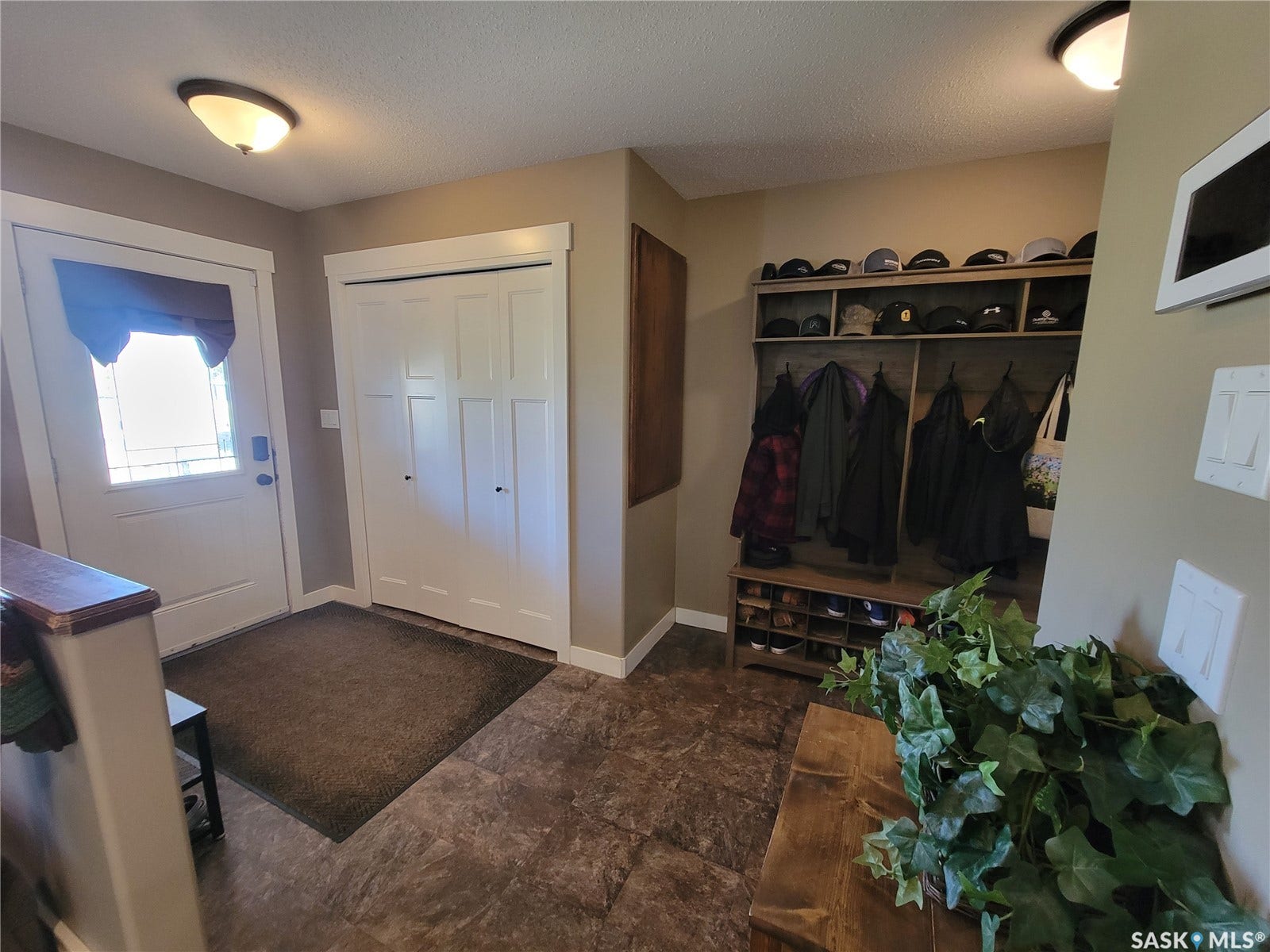 Entryway featuring a built-in hall tree with integrated storage, a white paneled entry door with decorative glass, and durable stone-look flooring