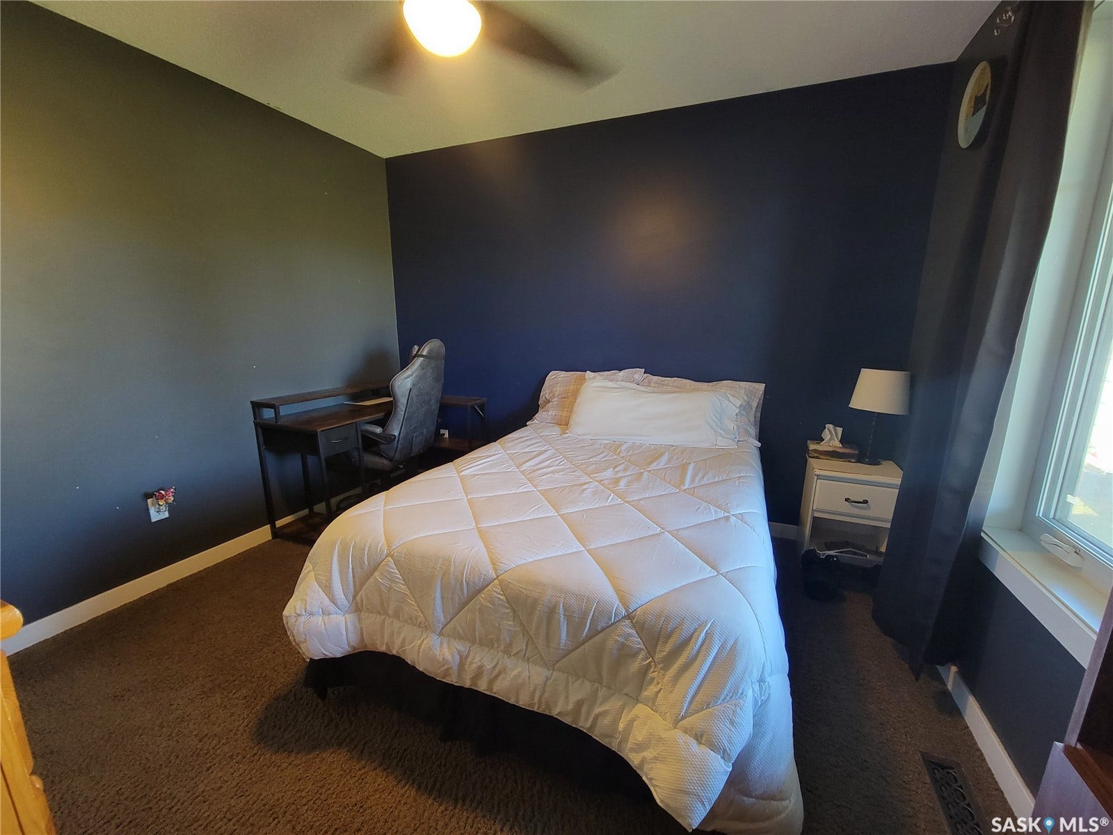 Integrated ceiling fan with light fixture, window with white trim, and dark carpeting