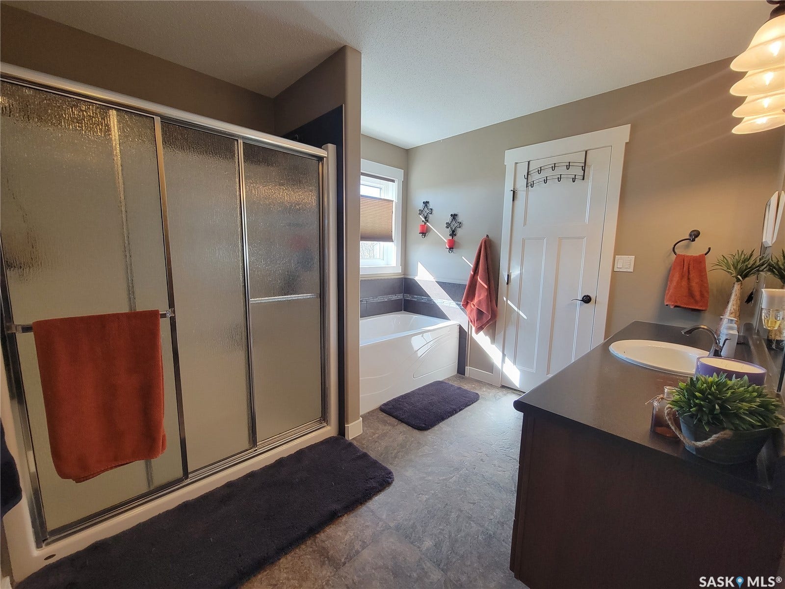 Enclosed shower with sliding frosted glass doors, a built-in bathtub, and a single vanity with an integrated sink and dark countertop