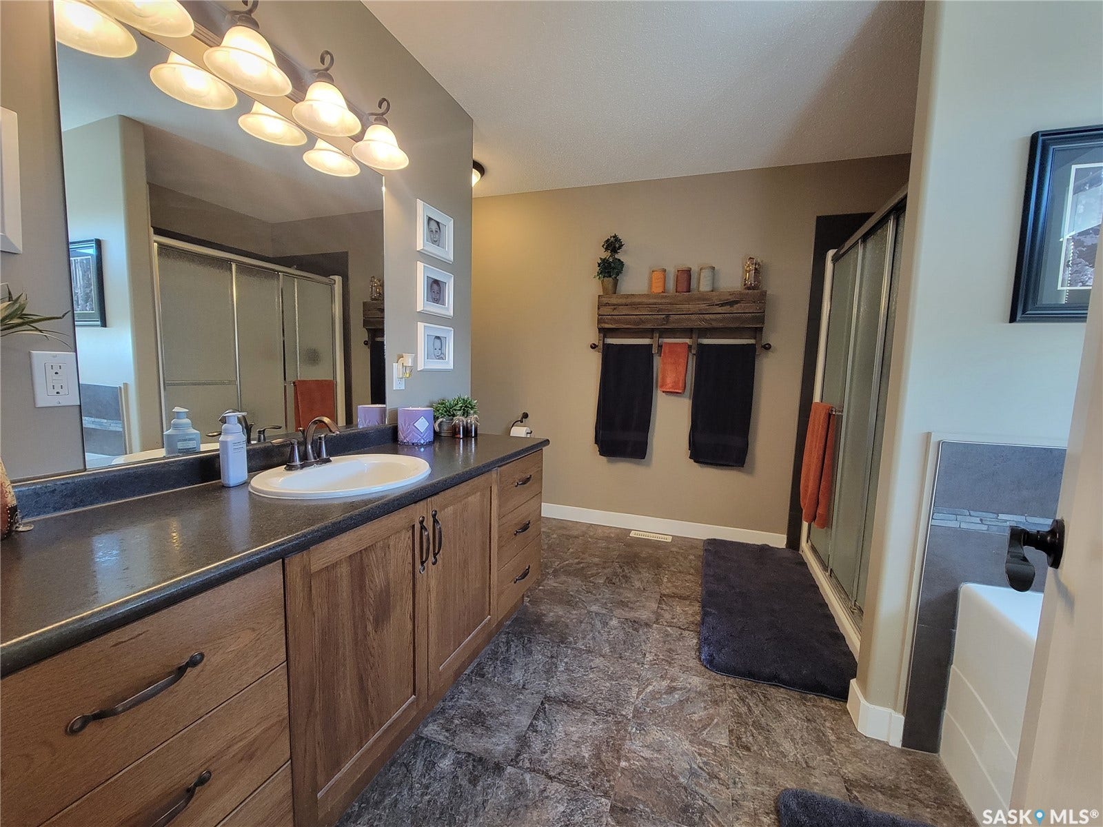 Elongated double vanity with wood-finish cabinetry, a single basin sink, and an expansive mirror