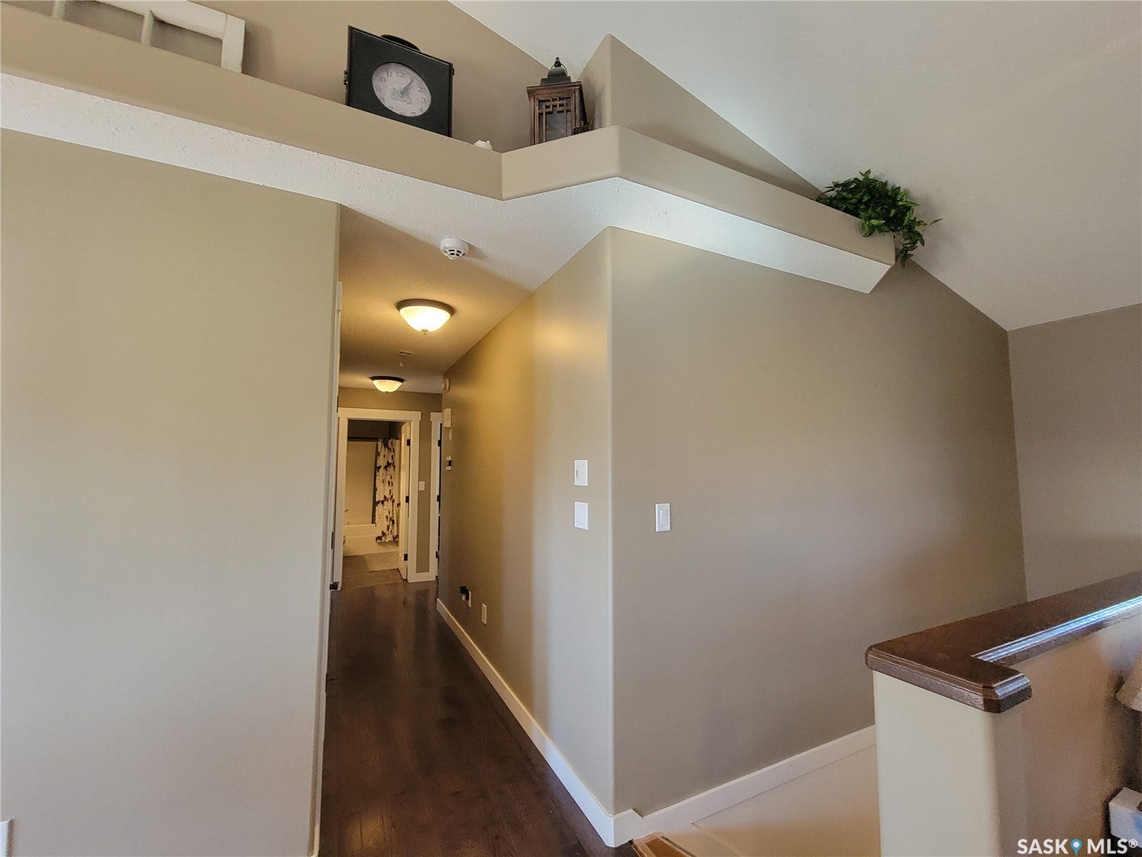 Hallway featuring wood-finish flooring, overhead flush mount lighting, and a wood handrail