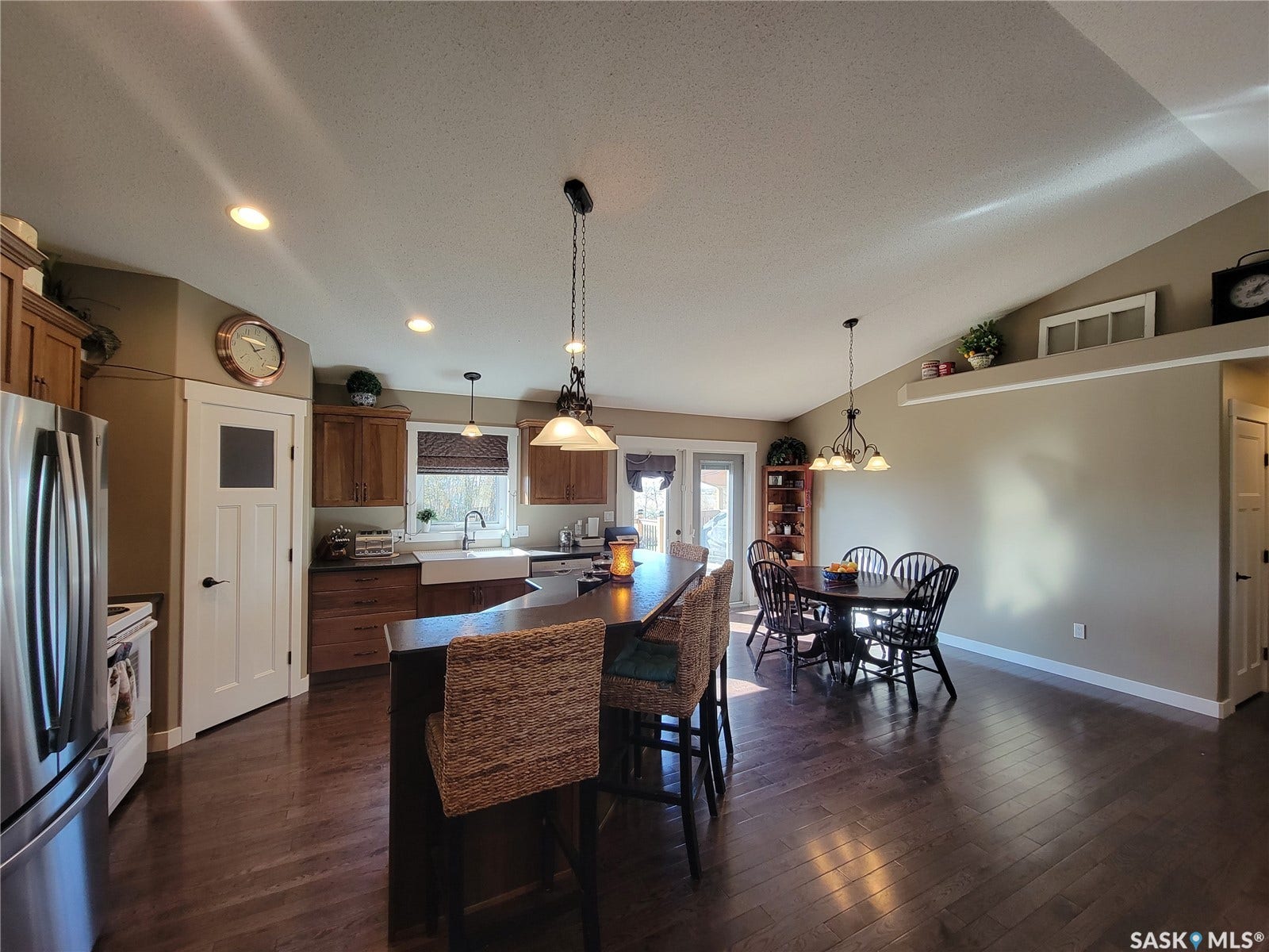 Open-concept living space with dark wood-finish flooring, recessed lighting, and a vaulted ceiling