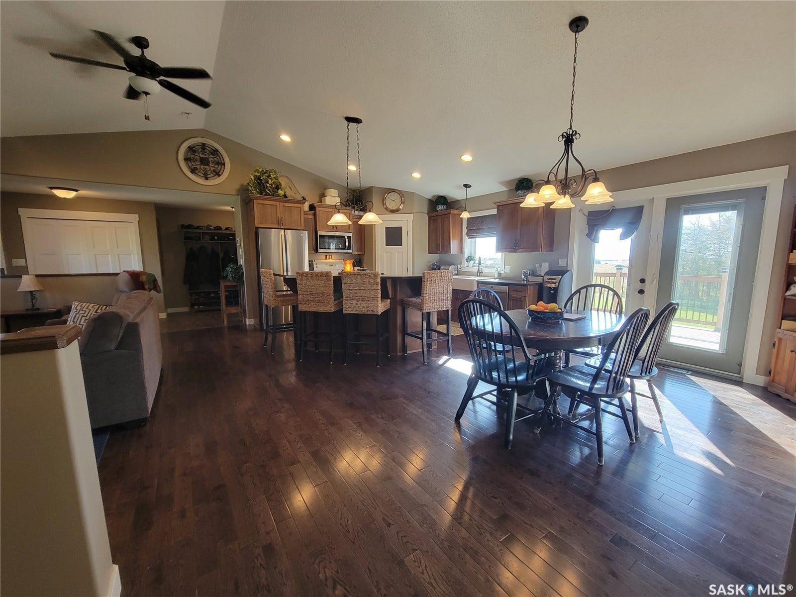 Expansive wood-finish flooring throughout, vaulted ceilings with ceiling fan, recessed lighting, kitchen island with seating, and stainless steel appliances