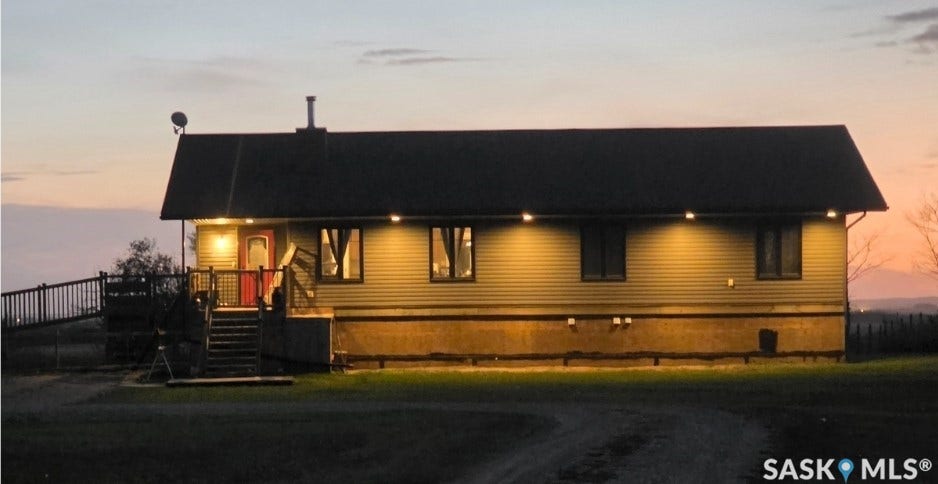 Siding exterior with a red entry door, elevated deck, and a sloped roofline