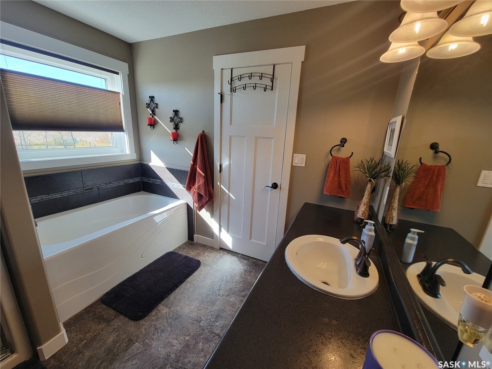 Built-in bathtub with a tiled surround, single vanity with an integrated sink, and an expansive mirror