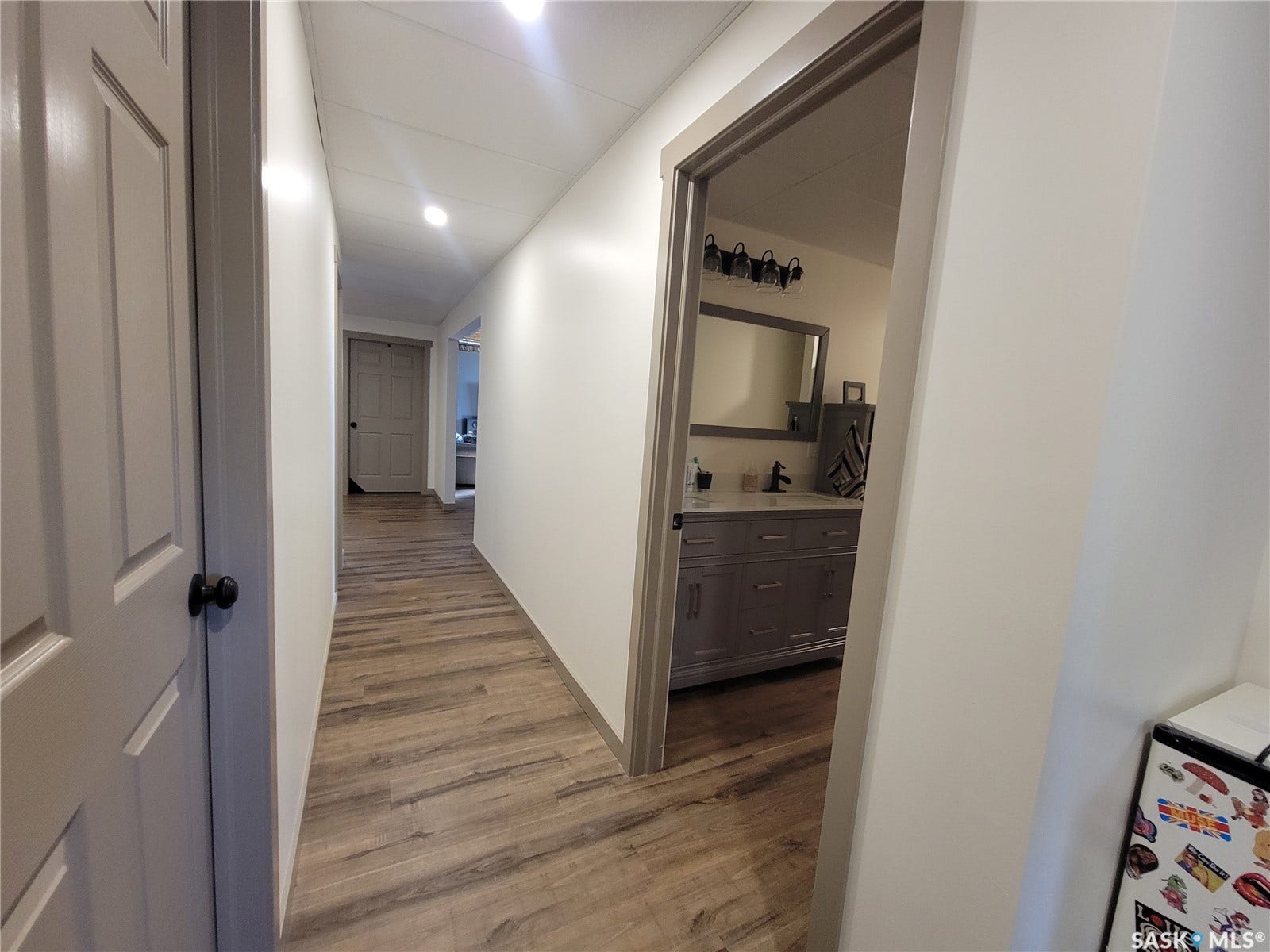 Hallway with wood-finish flooring, recessed lighting, and white paneled doors
