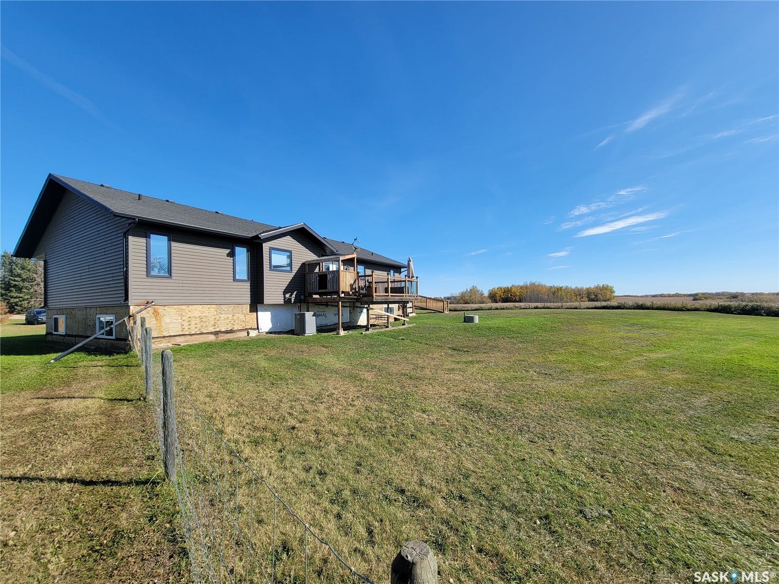 Expansive grounds featuring a wood deck, wood siding, and a wire fence