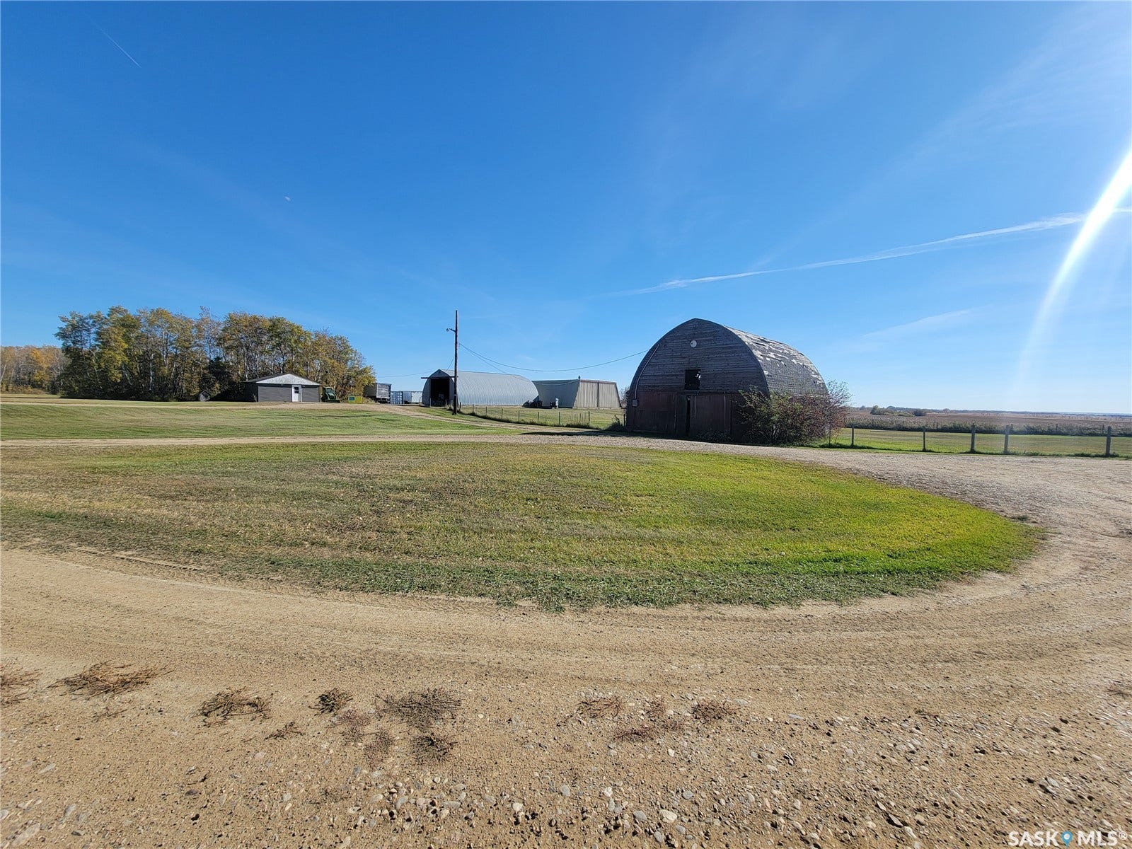 Expansive property featuring multiple outbuildings, a prominent Quonset-style barn, and open fields