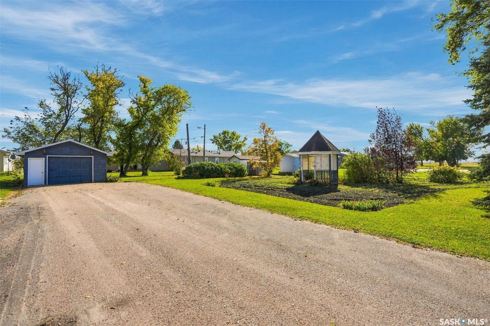 Detached garage with a roll-up door, gravel driveway, and a gazebo with a conical roof