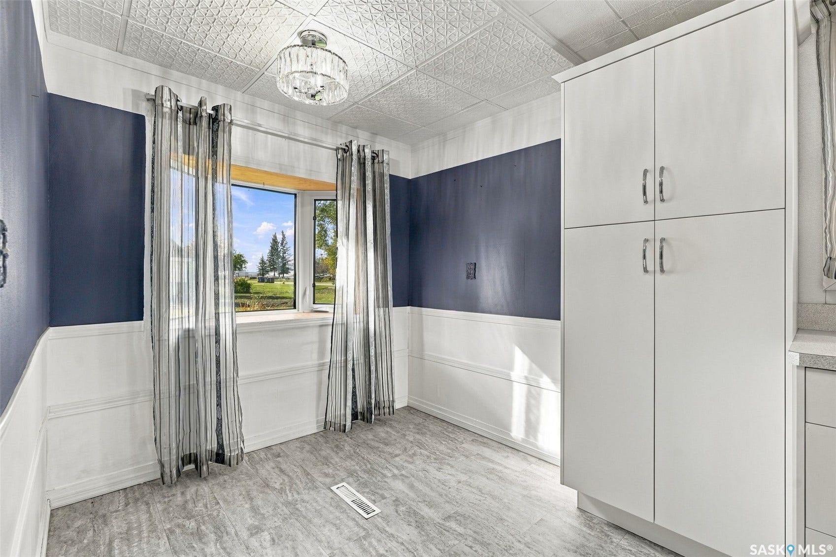 Bay window, wainscoting, textured ceiling, built-in cabinetry, overhead lighting