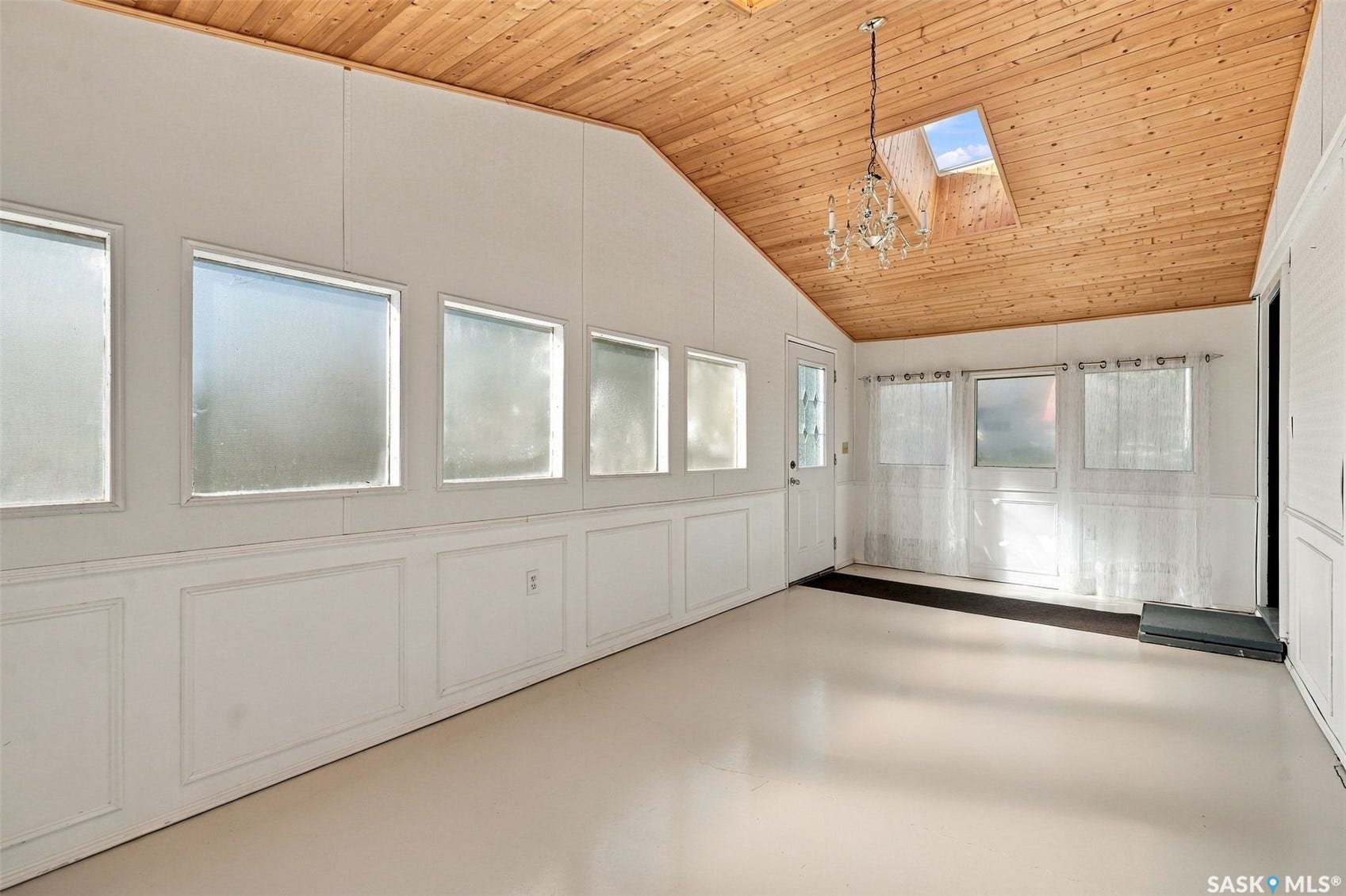 Vaulted wood-paneled ceiling with a skylight and chandelier