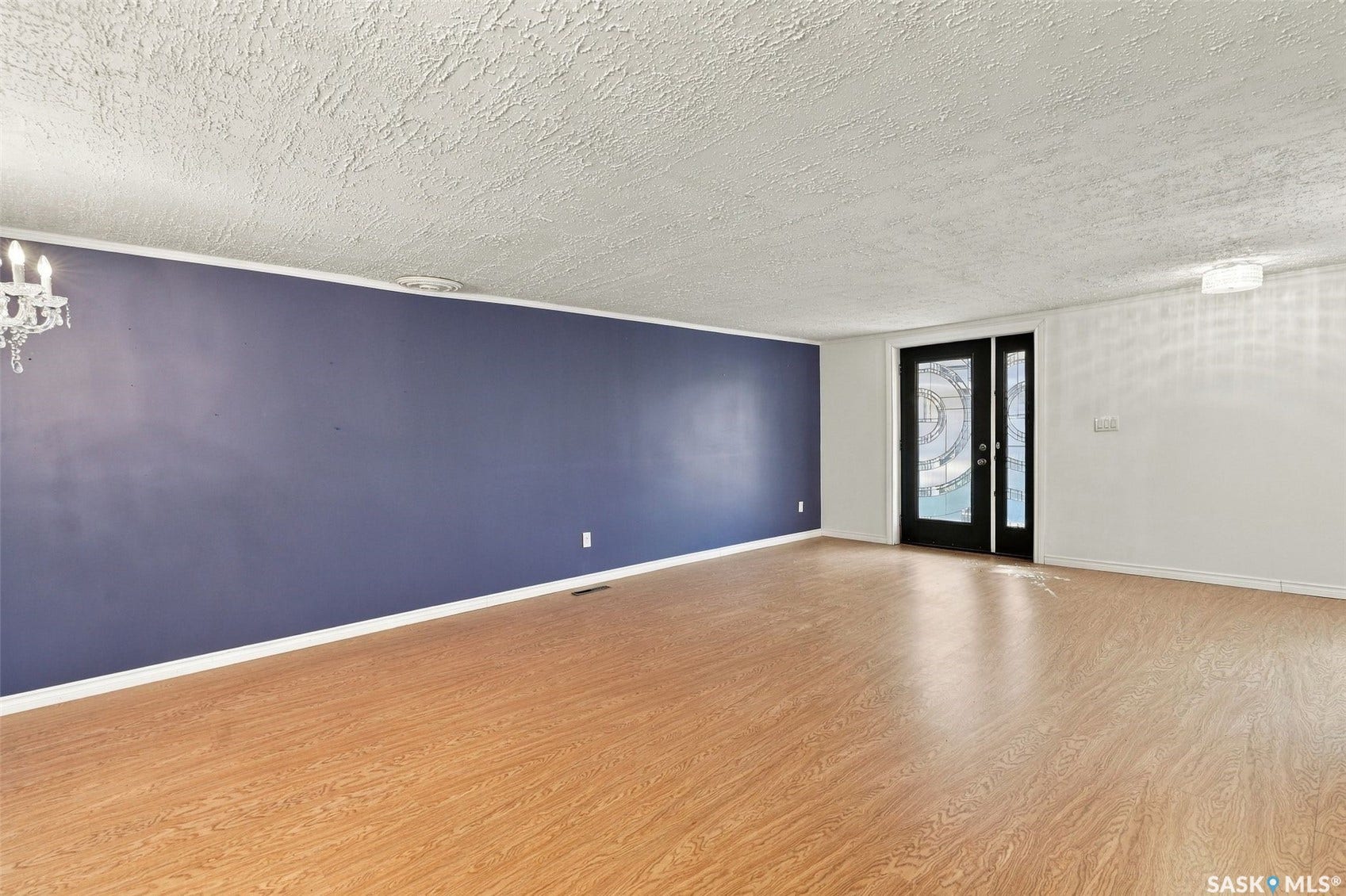 Wood-finish flooring throughout, featuring a dual-pane entry door with decorative glass, and a modern ceiling-mounted light fixture
