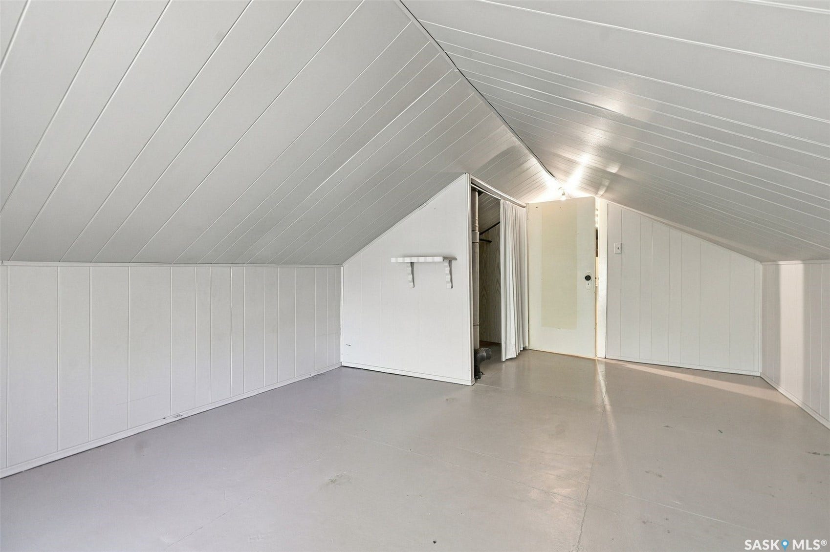 Sloped ceiling with paneling, white vertical paneling, and a built-in closet with a sliding door